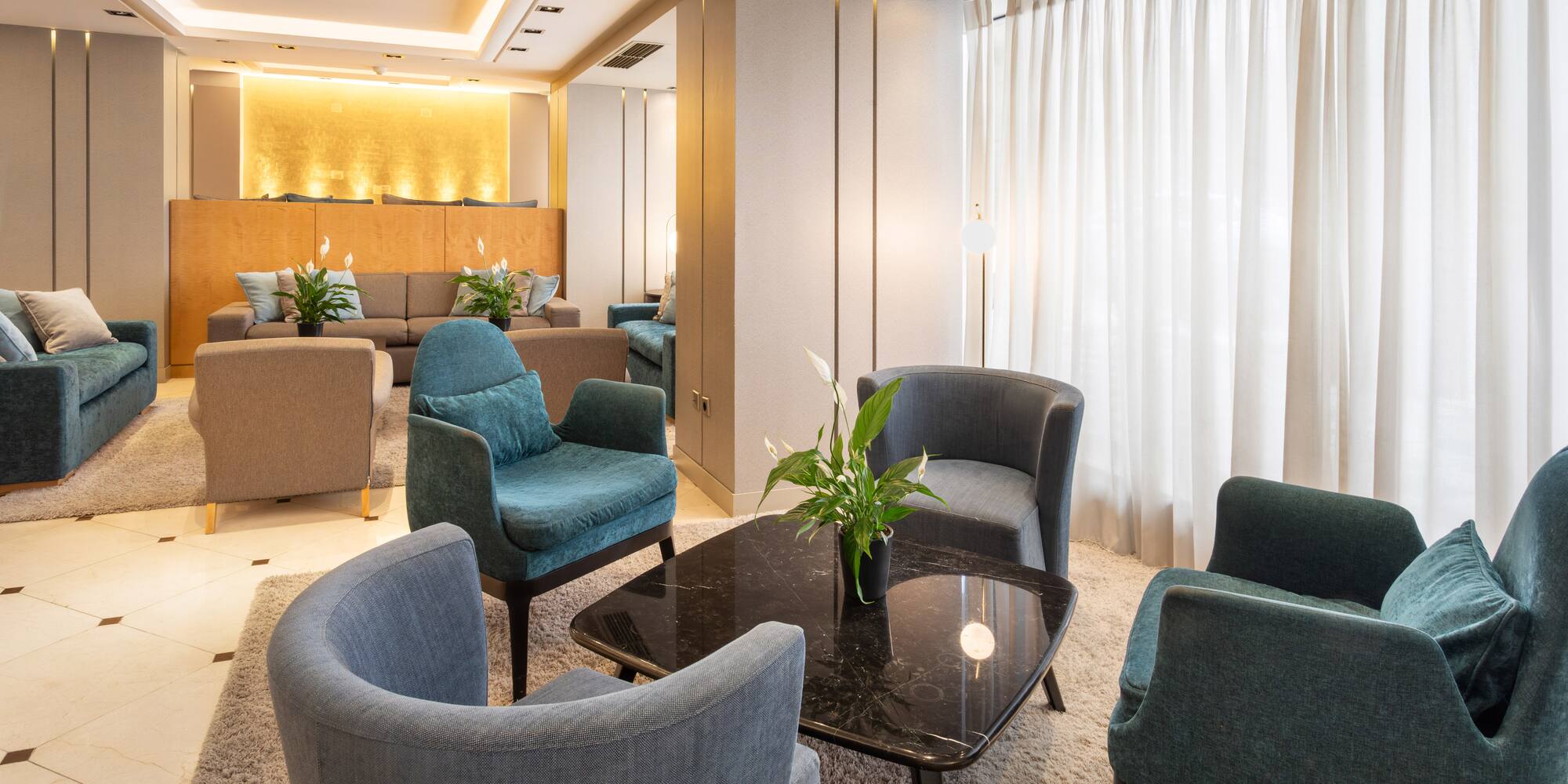 Modern hotel lounge with armchairs, coffee table, and warm lighting.