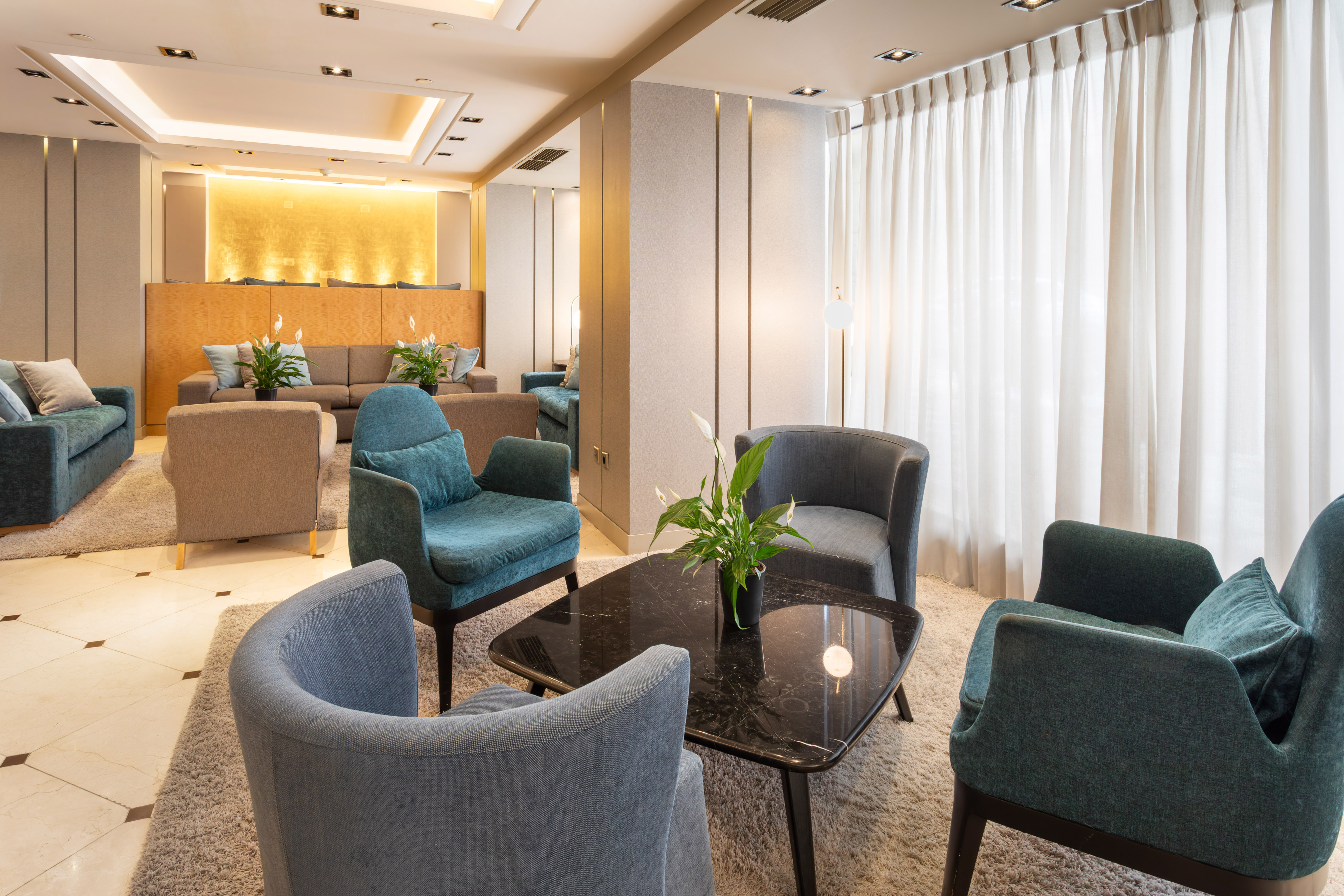 Modern hotel lounge with armchairs, coffee table, and warm lighting.