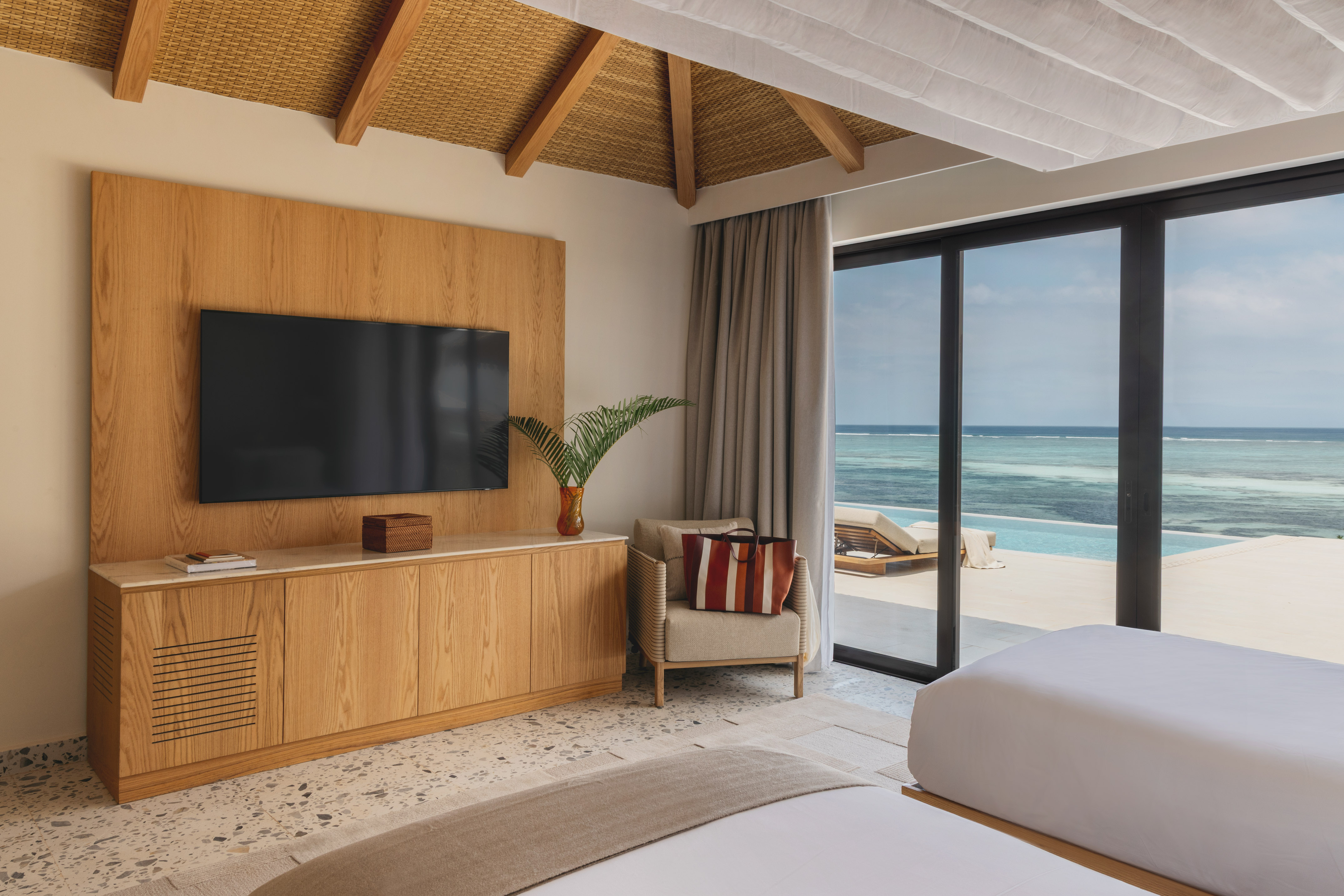 Oceanfront resort room with pool view, modern TV, and tropical decor.