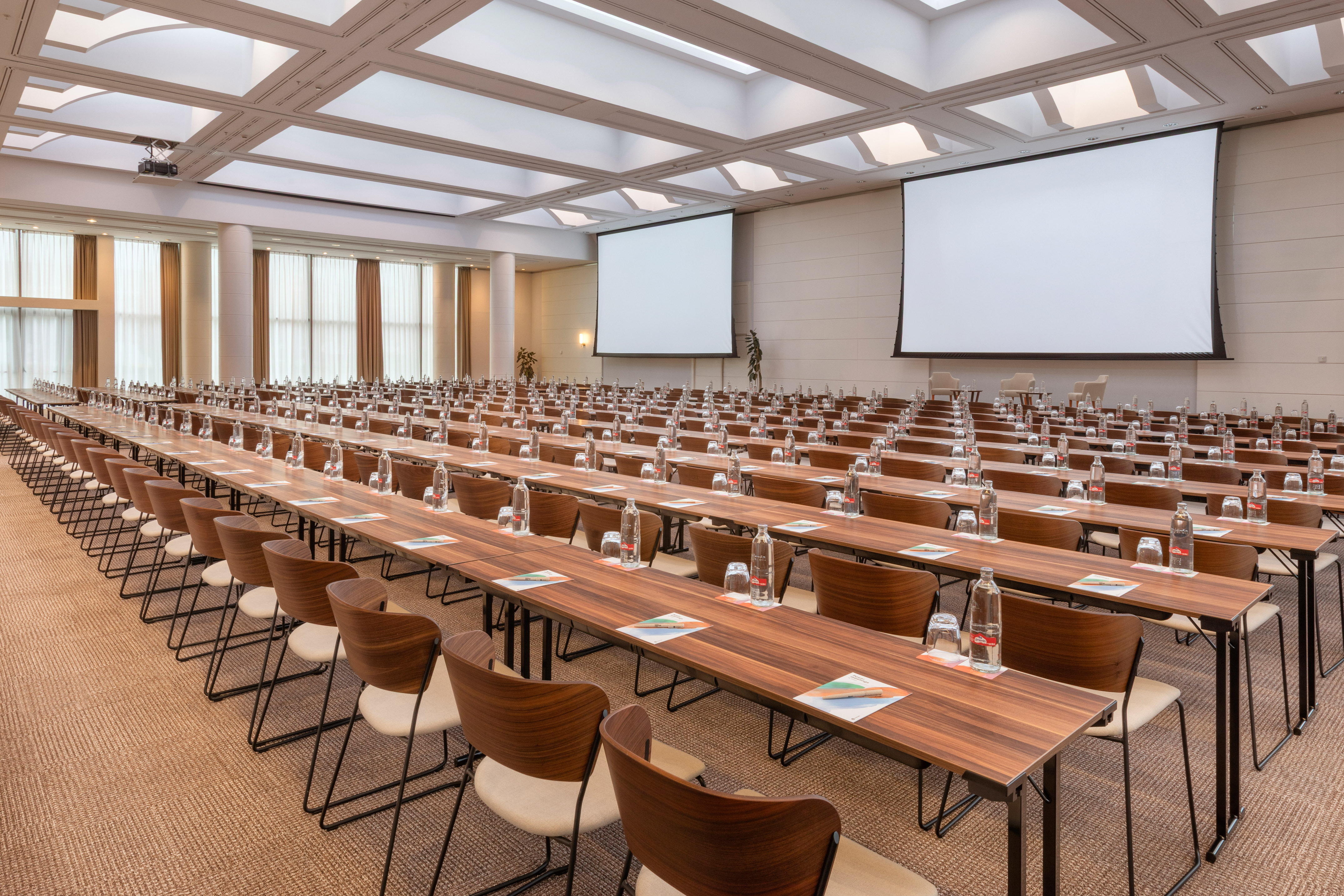 Large empty conference room with tables, chairs, and dual presentation screens.