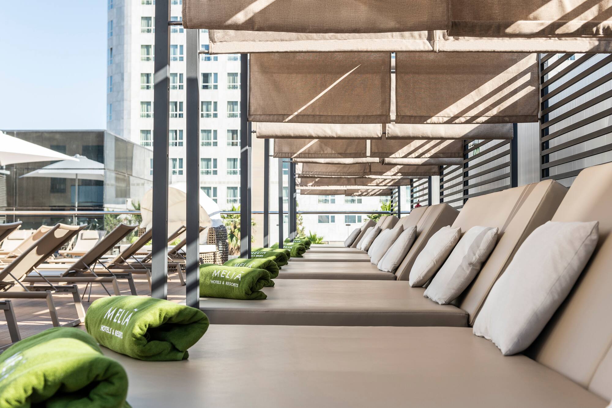 Meliá Hotels resort terrace with shaded sun loungers and green towels.