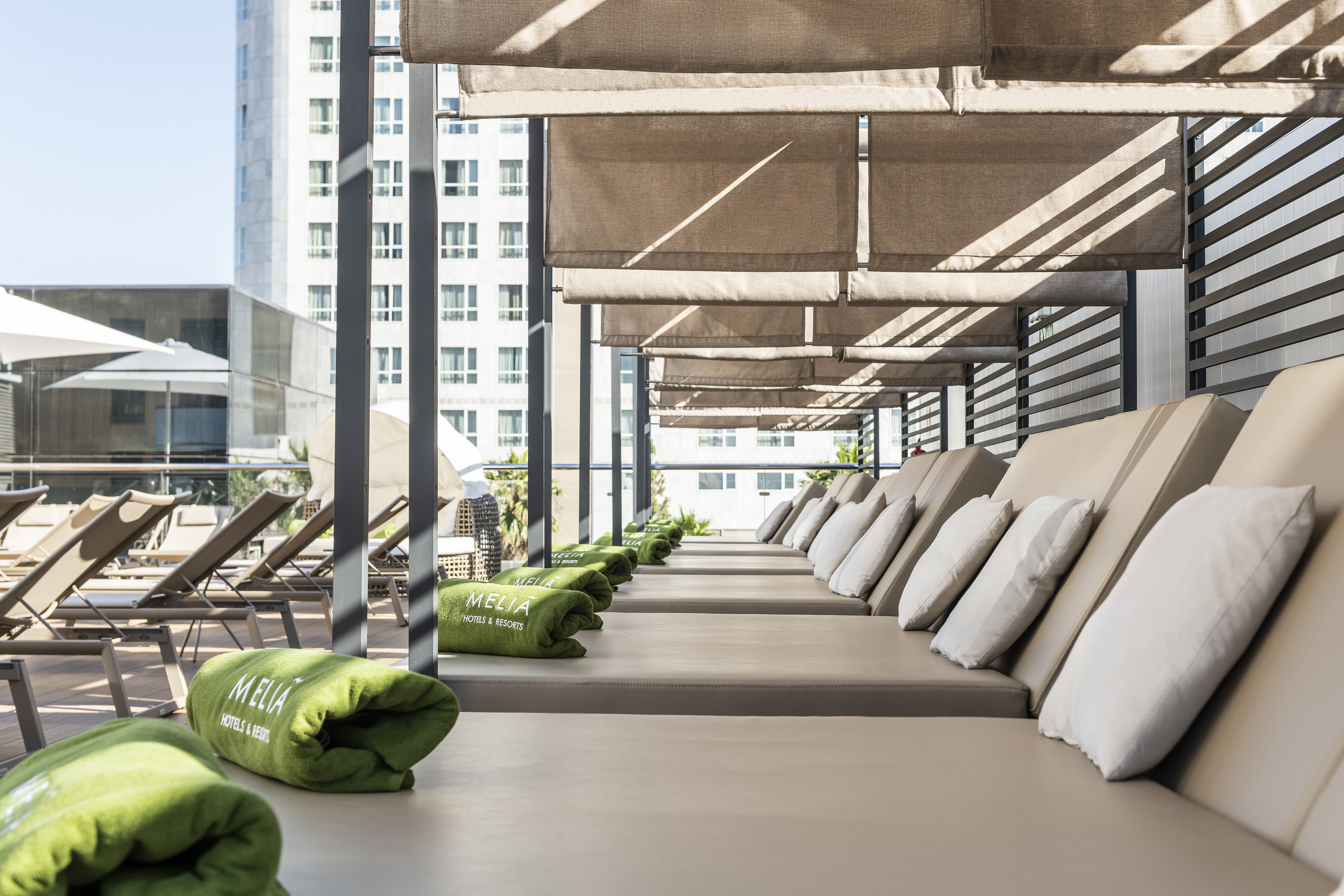 Meliá Hotels resort terrace with shaded sun loungers and green towels.