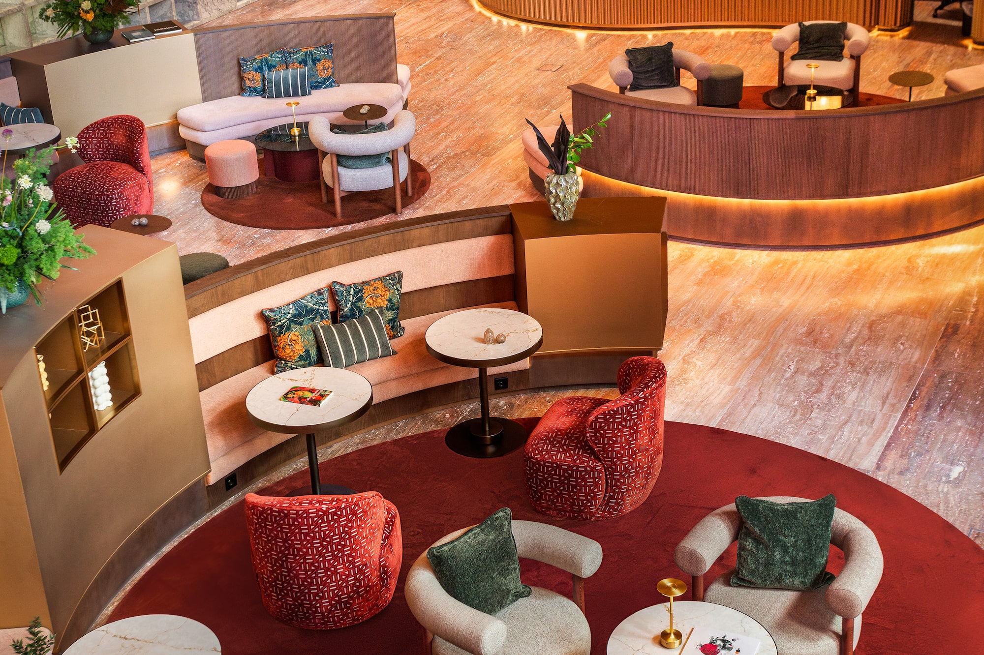 Modern hotel lobby with curved reception desk, red carpet, and comfortable seating.