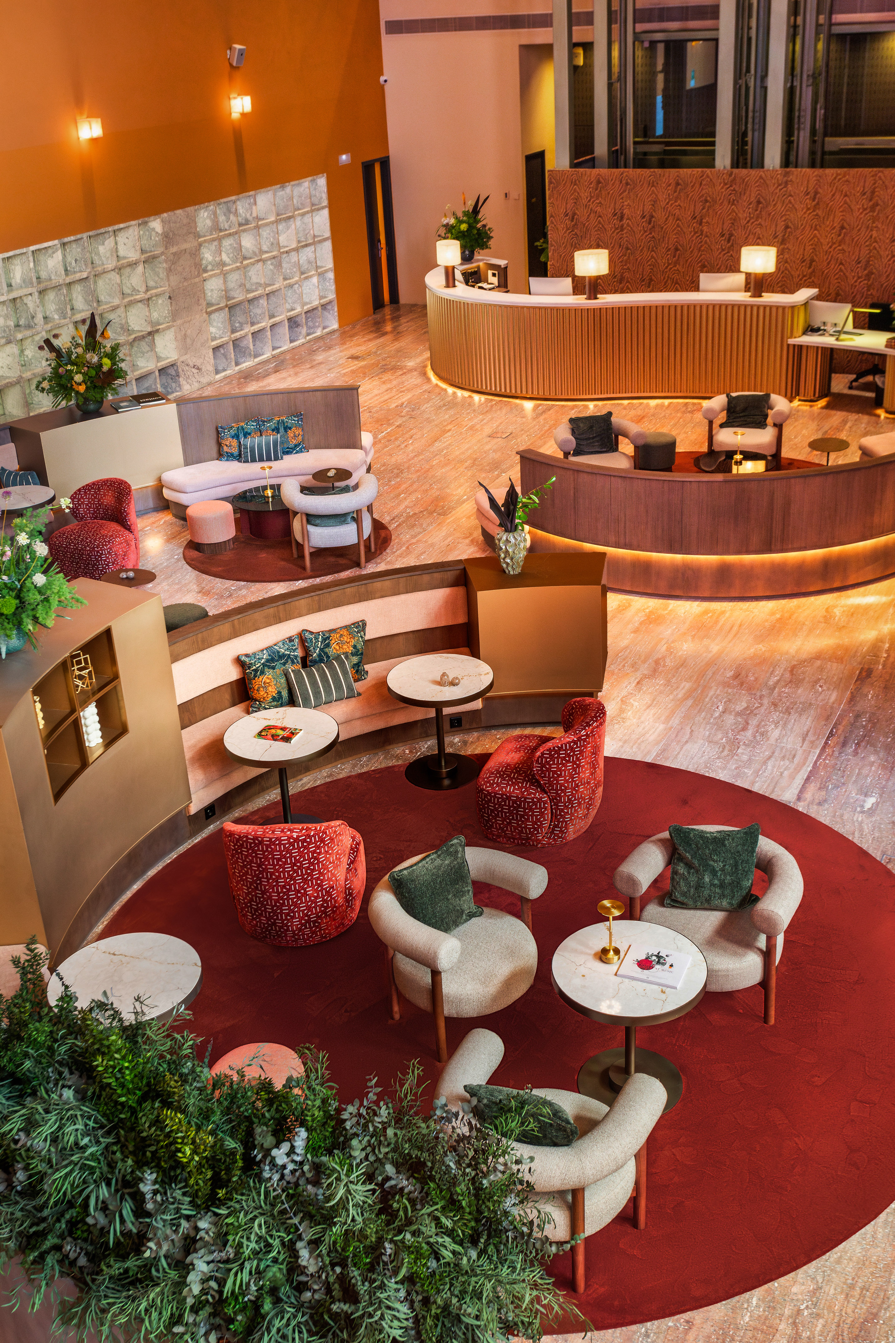 Modern hotel lobby with curved reception desk, red carpet, and comfortable seating.