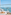 Balcony daybed with ocean view, distant island, straw hat, and glass railing.