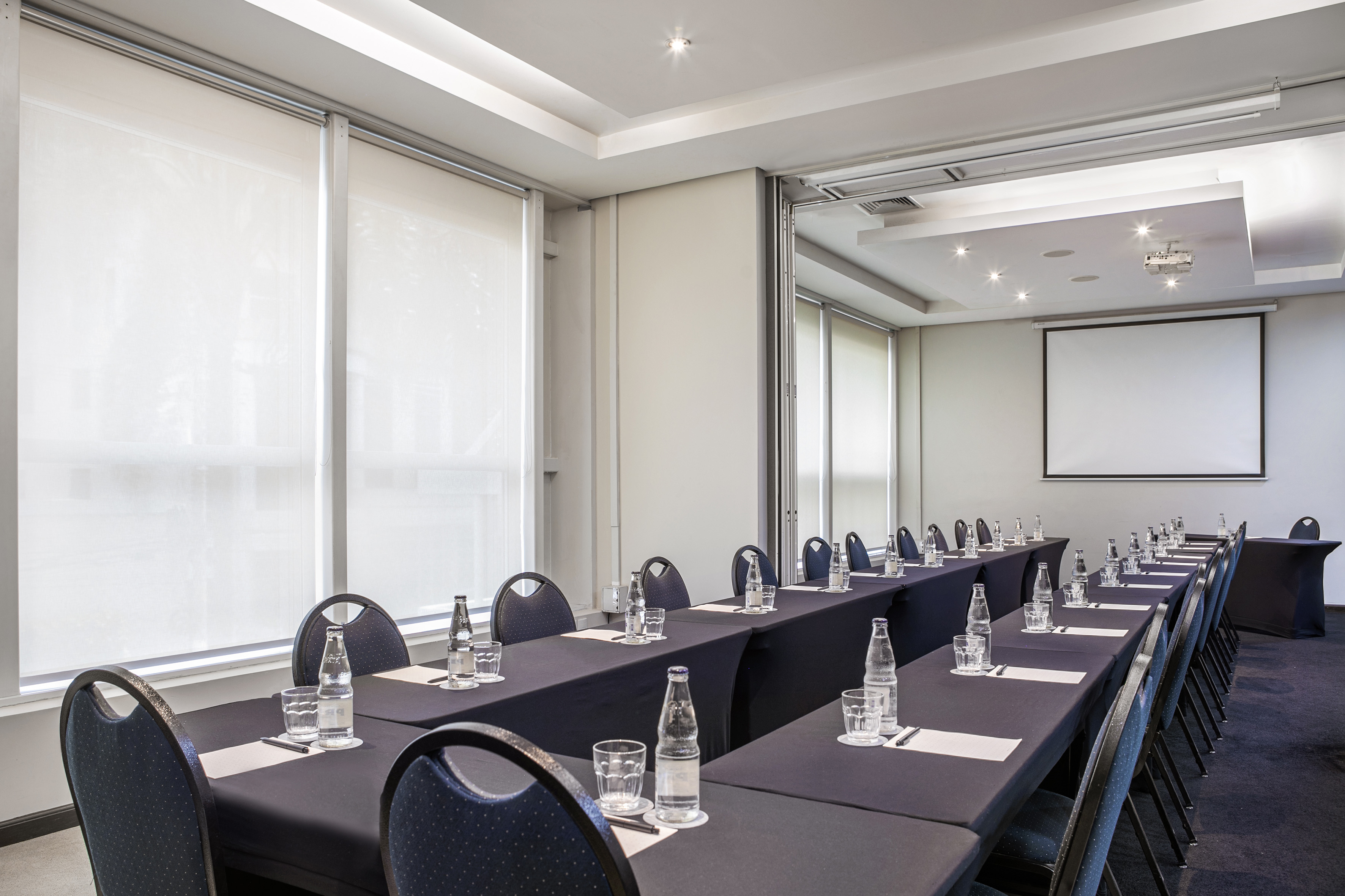 Equipped conference room with tables, projector screen, and refreshments.