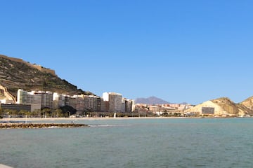 a body of water with buildings and mountains in the background