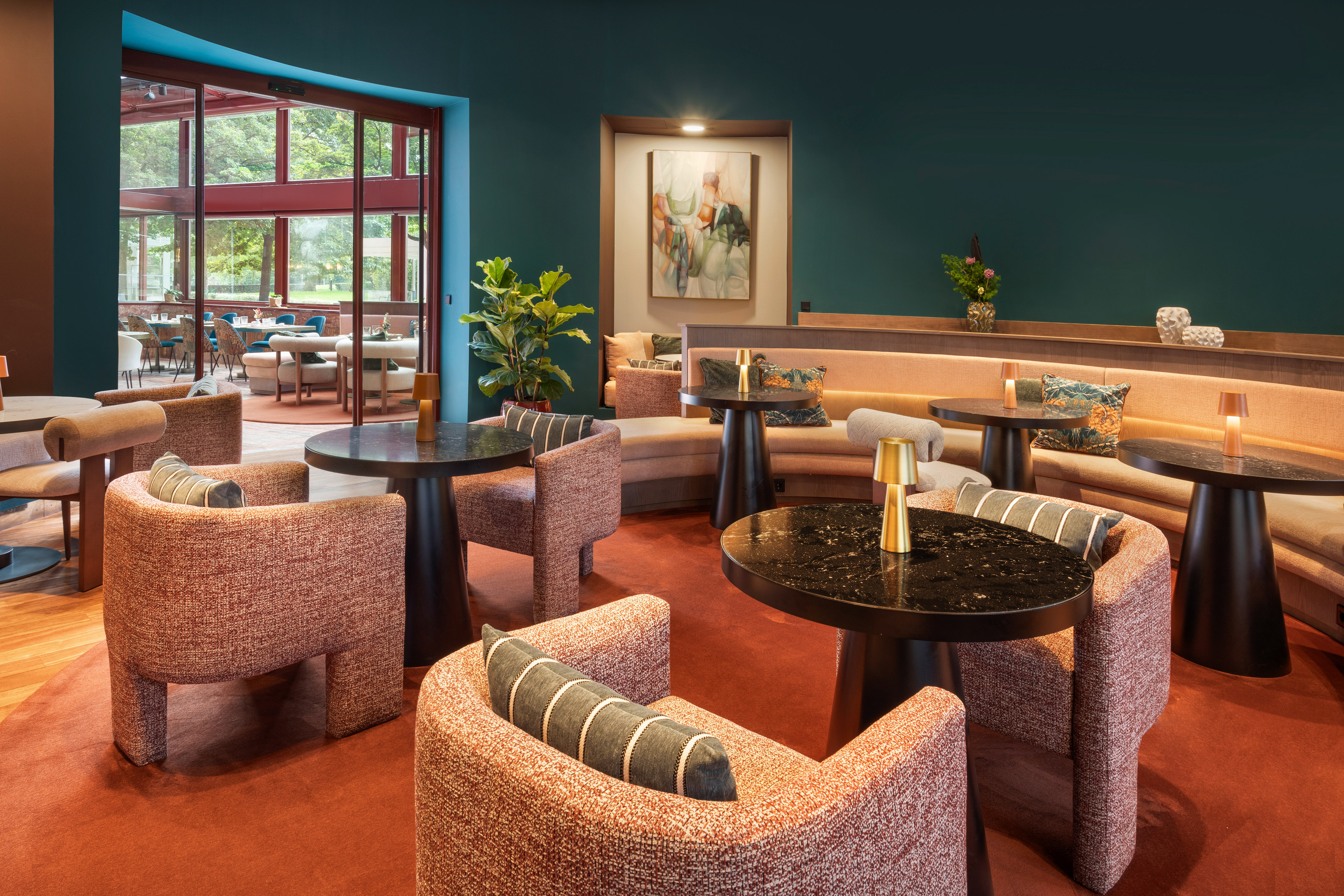 Modern lounge with orange seating, teal walls, and garden view.