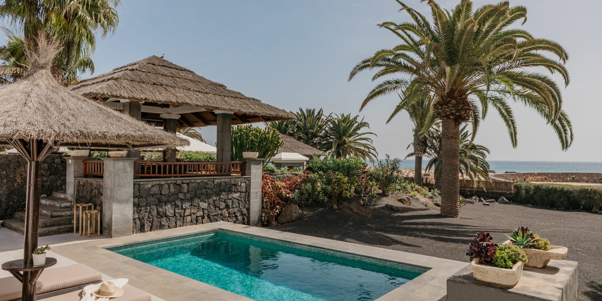 a pool with a straw roof and palm trees