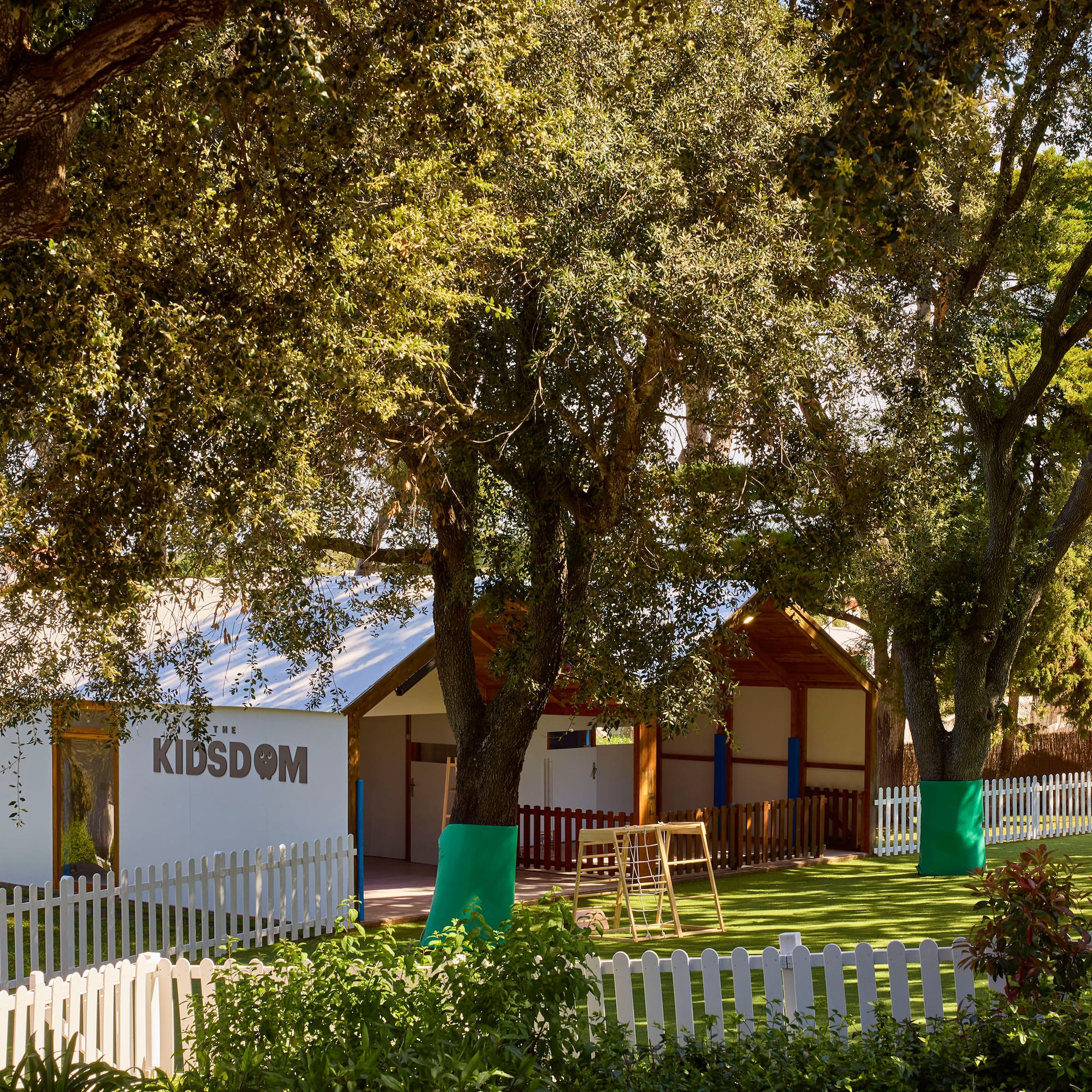 a white building with a white fence and trees