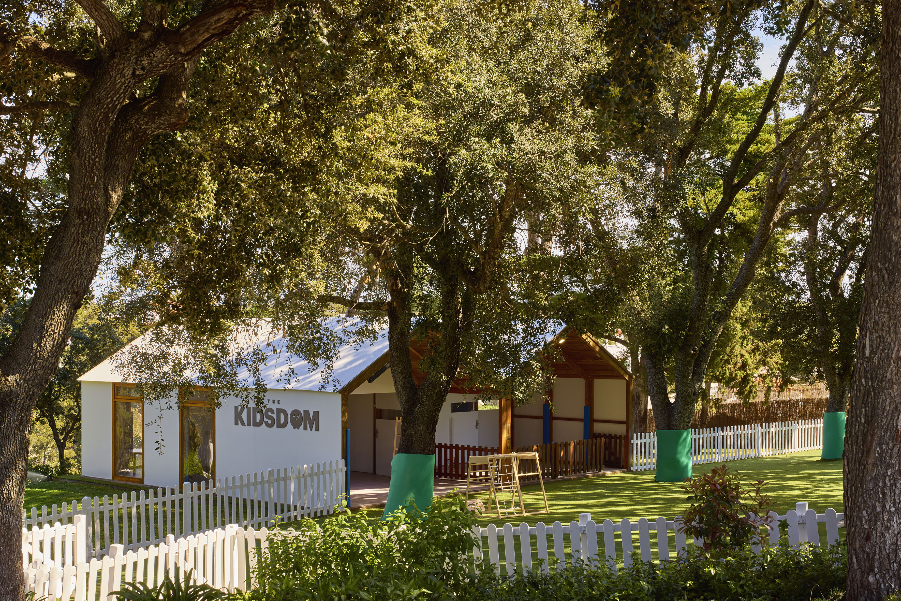a white building with a white fence and trees