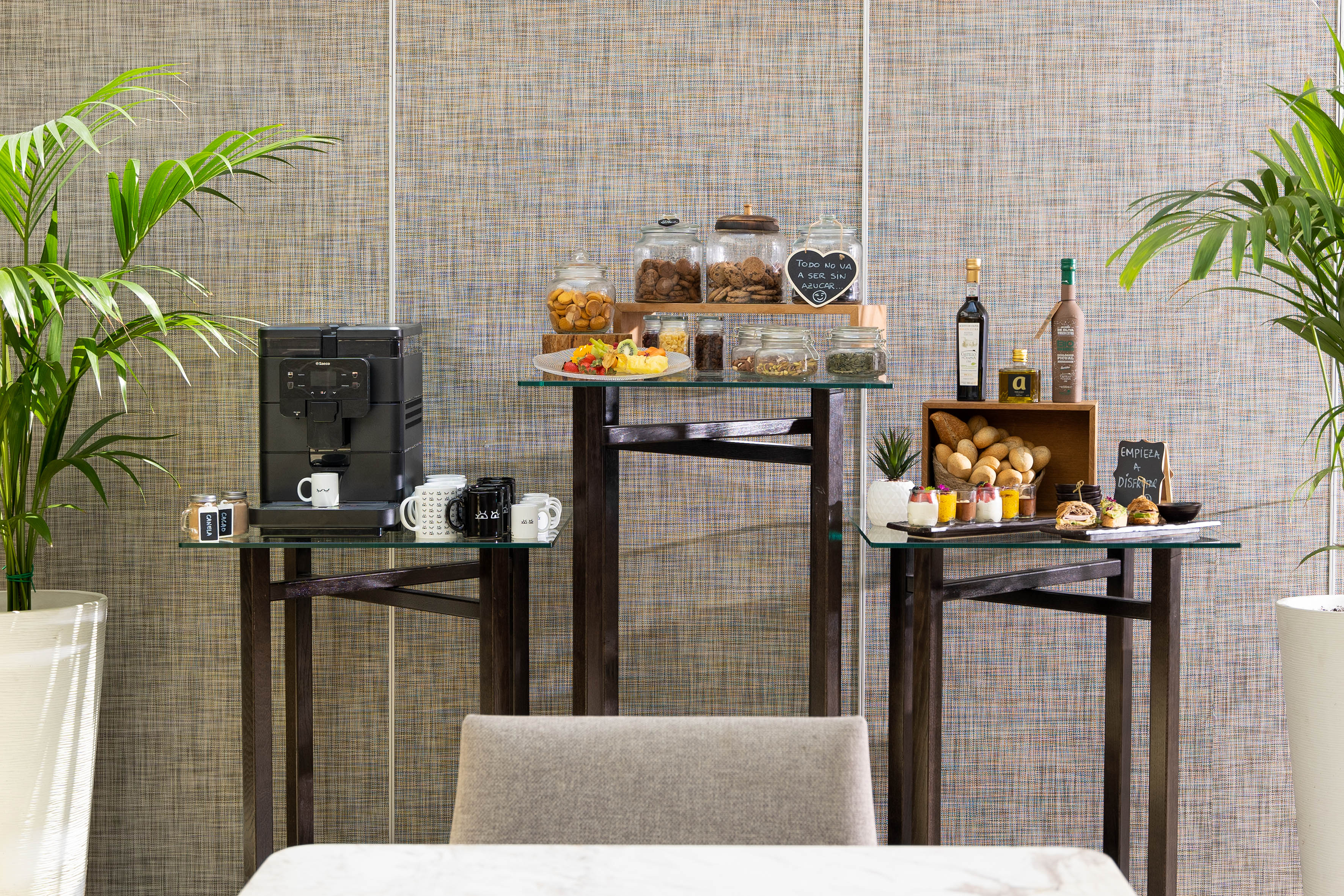Self-service breakfast bar with coffee machine, cookies, fruit salad, bread, and snacks.