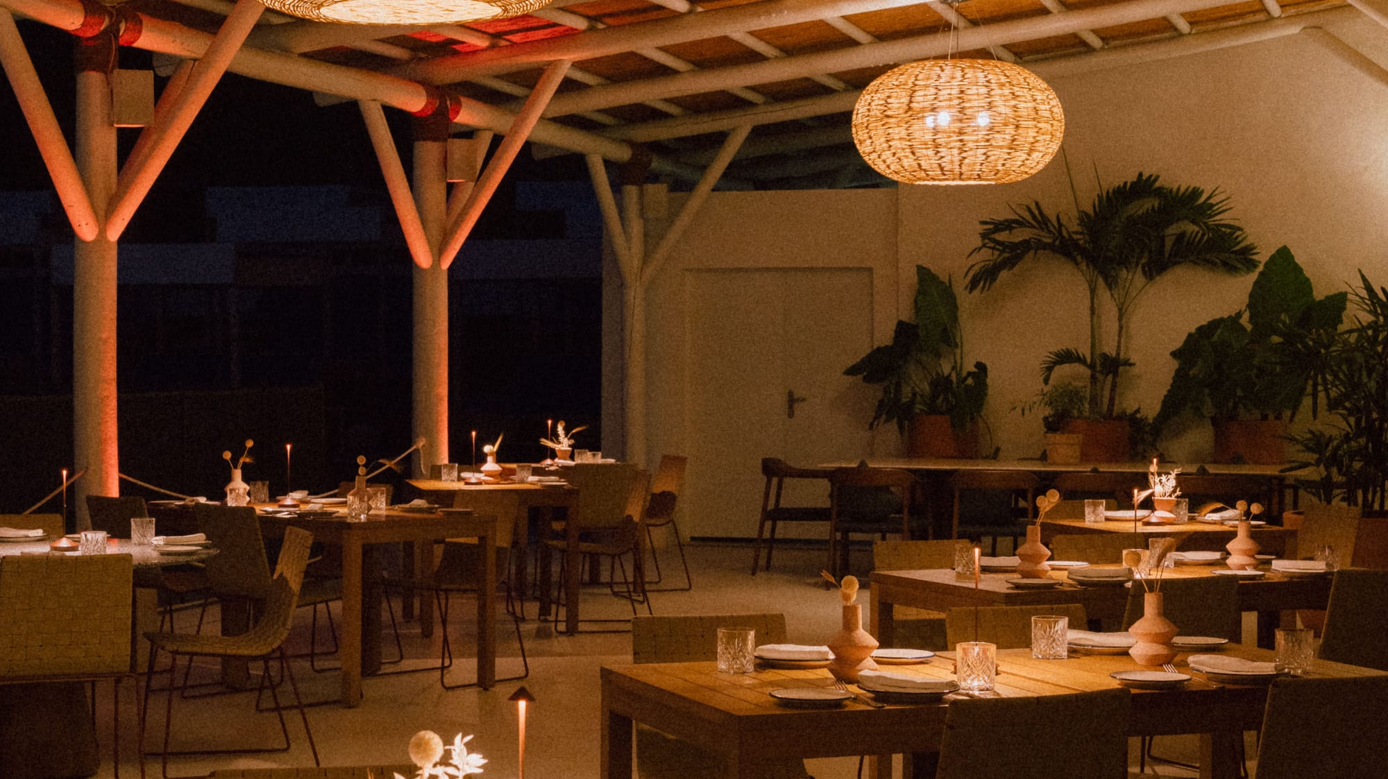 Warmly lit restaurant featuring bamboo ceiling, rattan lamps, and set tables.