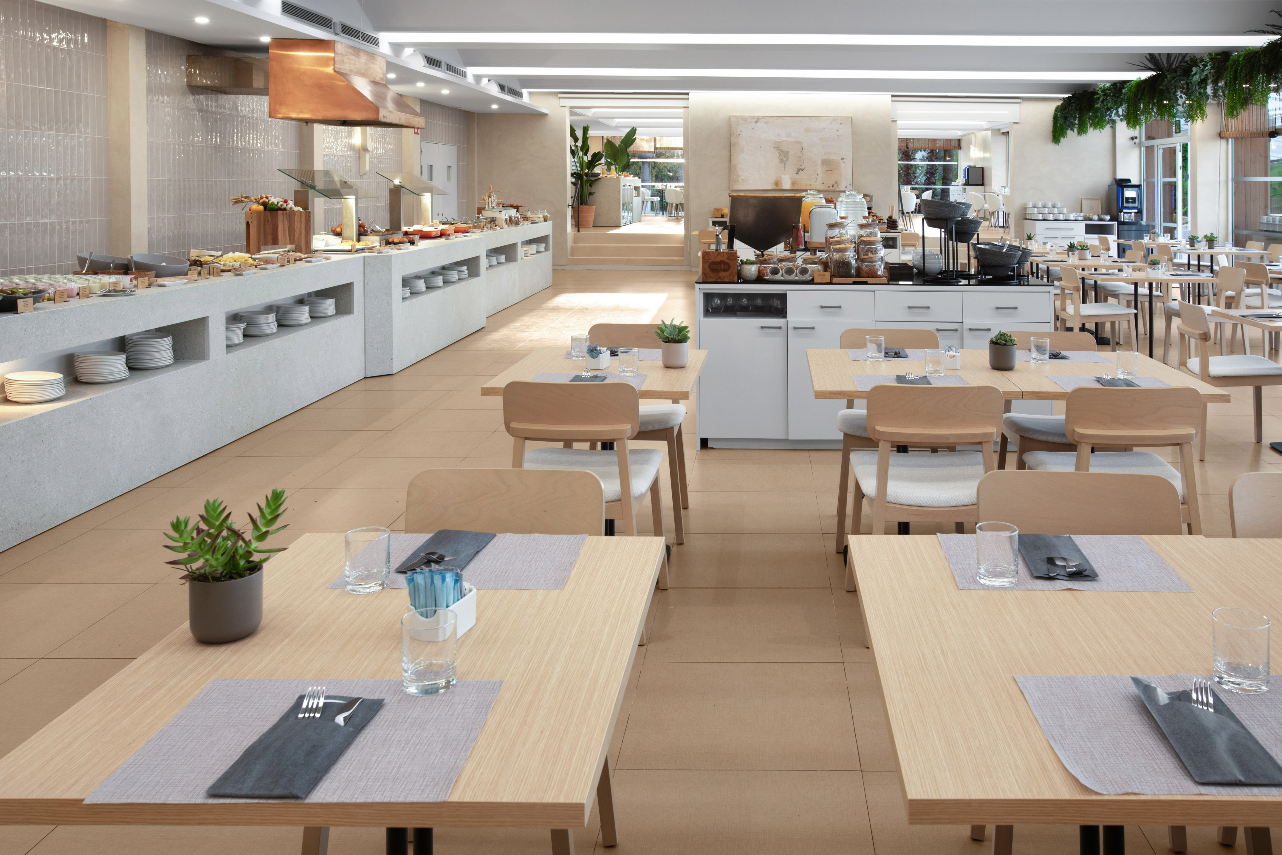 Modern hotel restaurant buffet with clean dining tables set for breakfast.