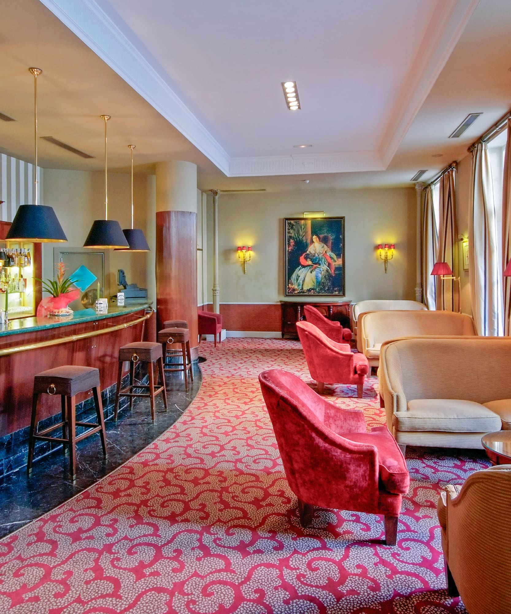 Bar de hotel elegante con barra de madera, alfombra roja y cómodos sofás.
