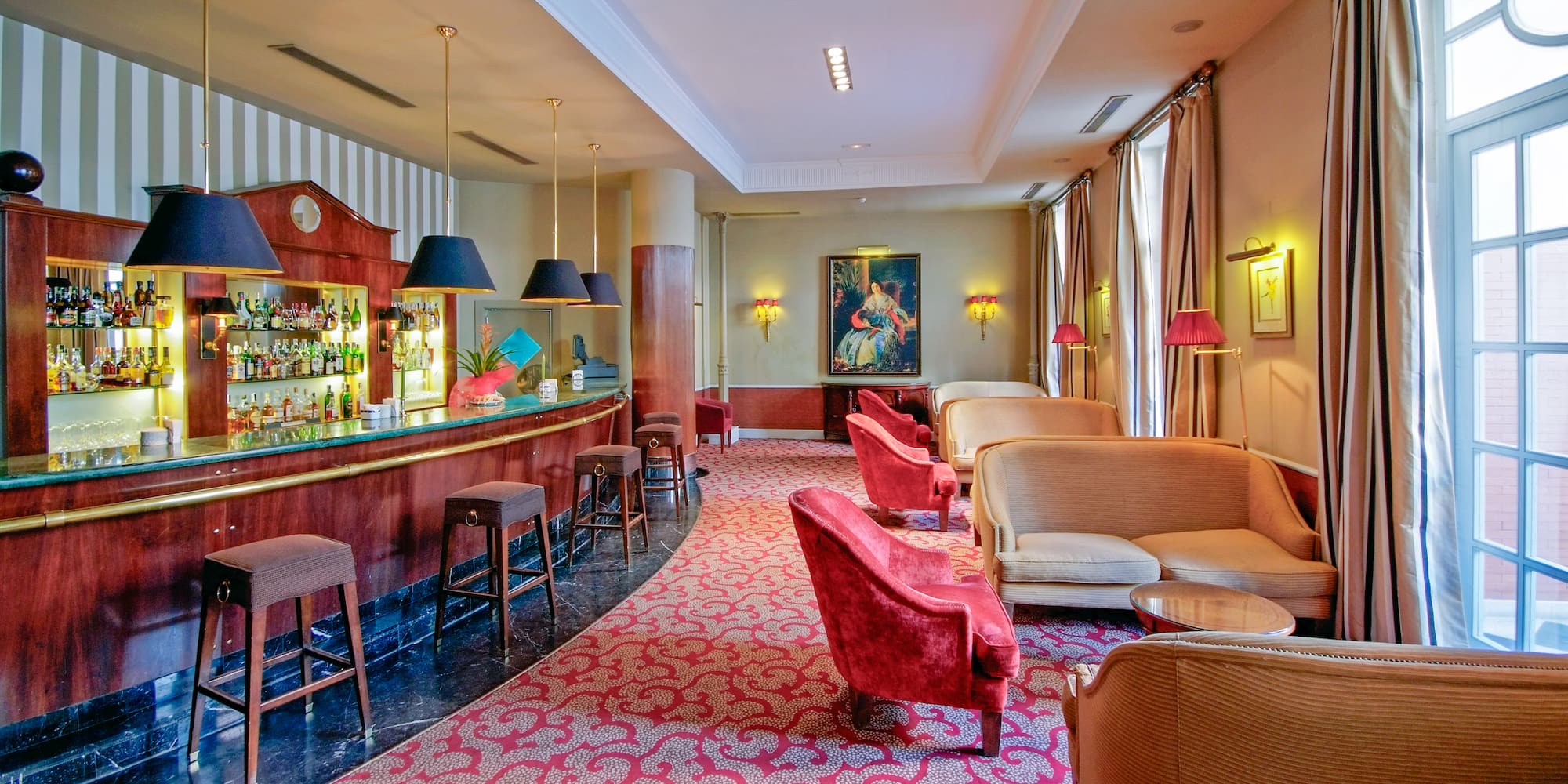 Hotel bar and lounge: dark wood bar, red seating, rich patterned carpet.