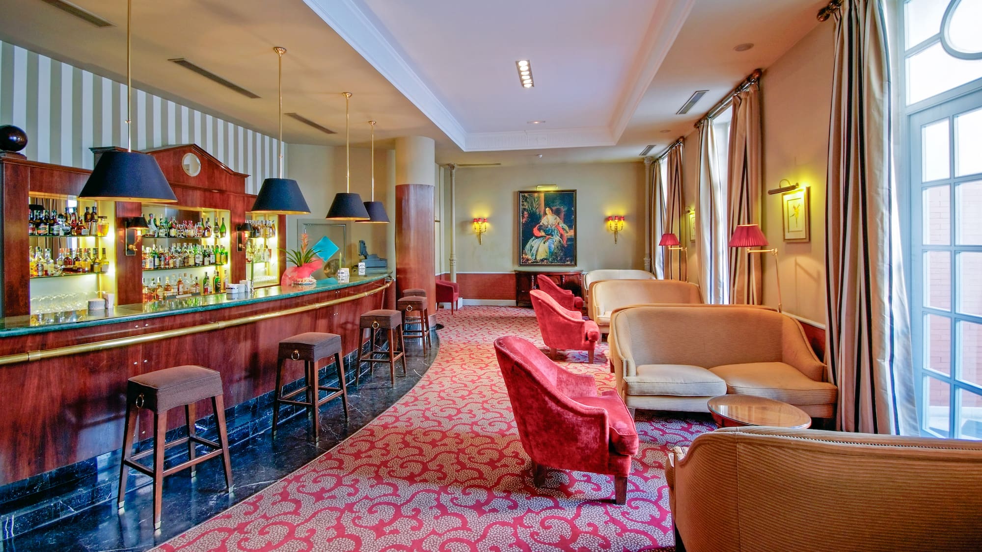 Hotel bar and lounge: dark wood bar, red seating, rich patterned carpet.