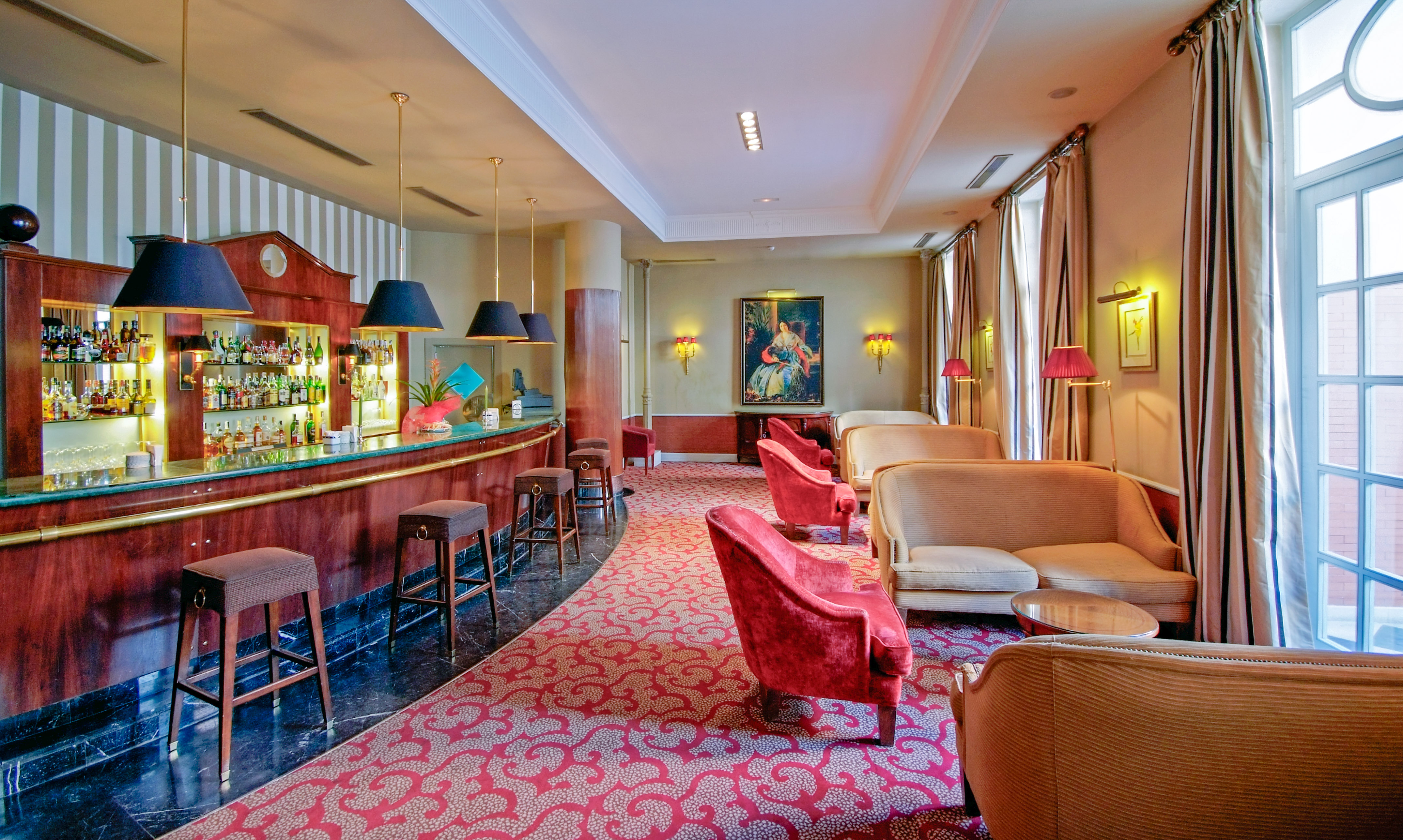 Hotel bar and lounge: dark wood bar, red seating, rich patterned carpet.