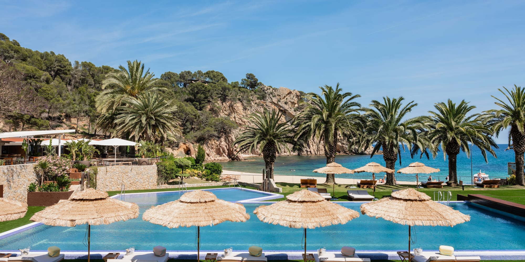a pool with umbrellas and lounge chairs on grass