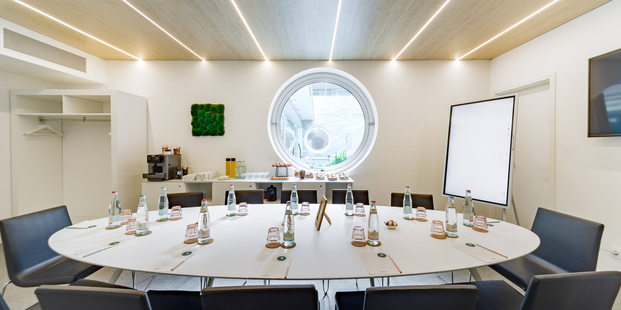 a round table with bottles of water and chairs in a room with a round window