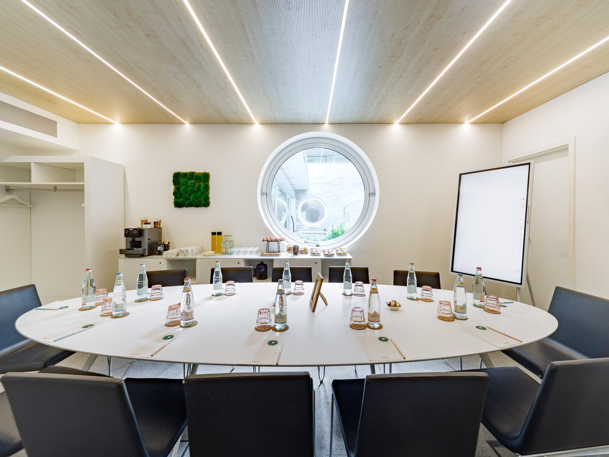 a round table with bottles of water and chairs in a room with a round window