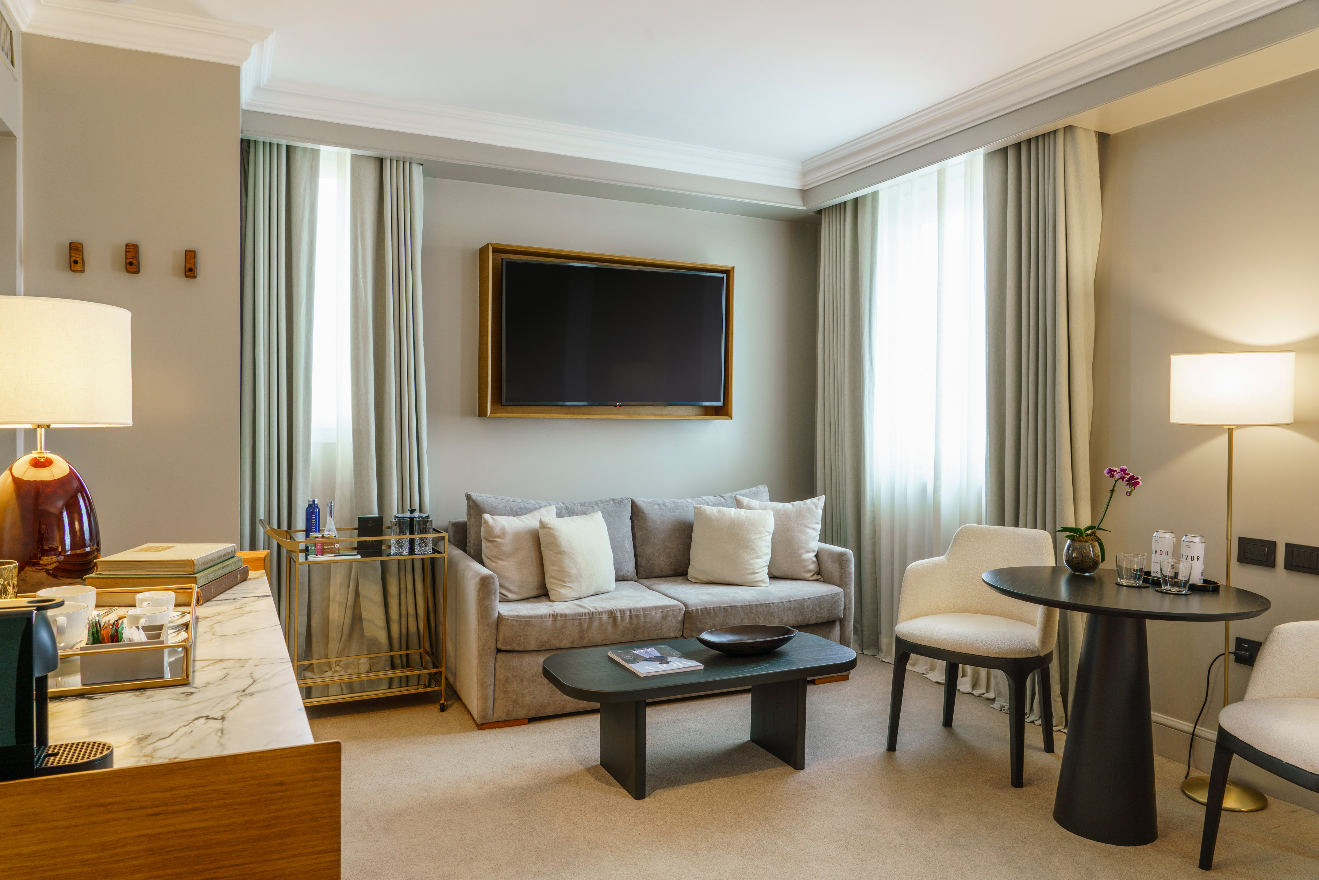 Elegant hotel suite living room with sofa, TV, and modern decor.