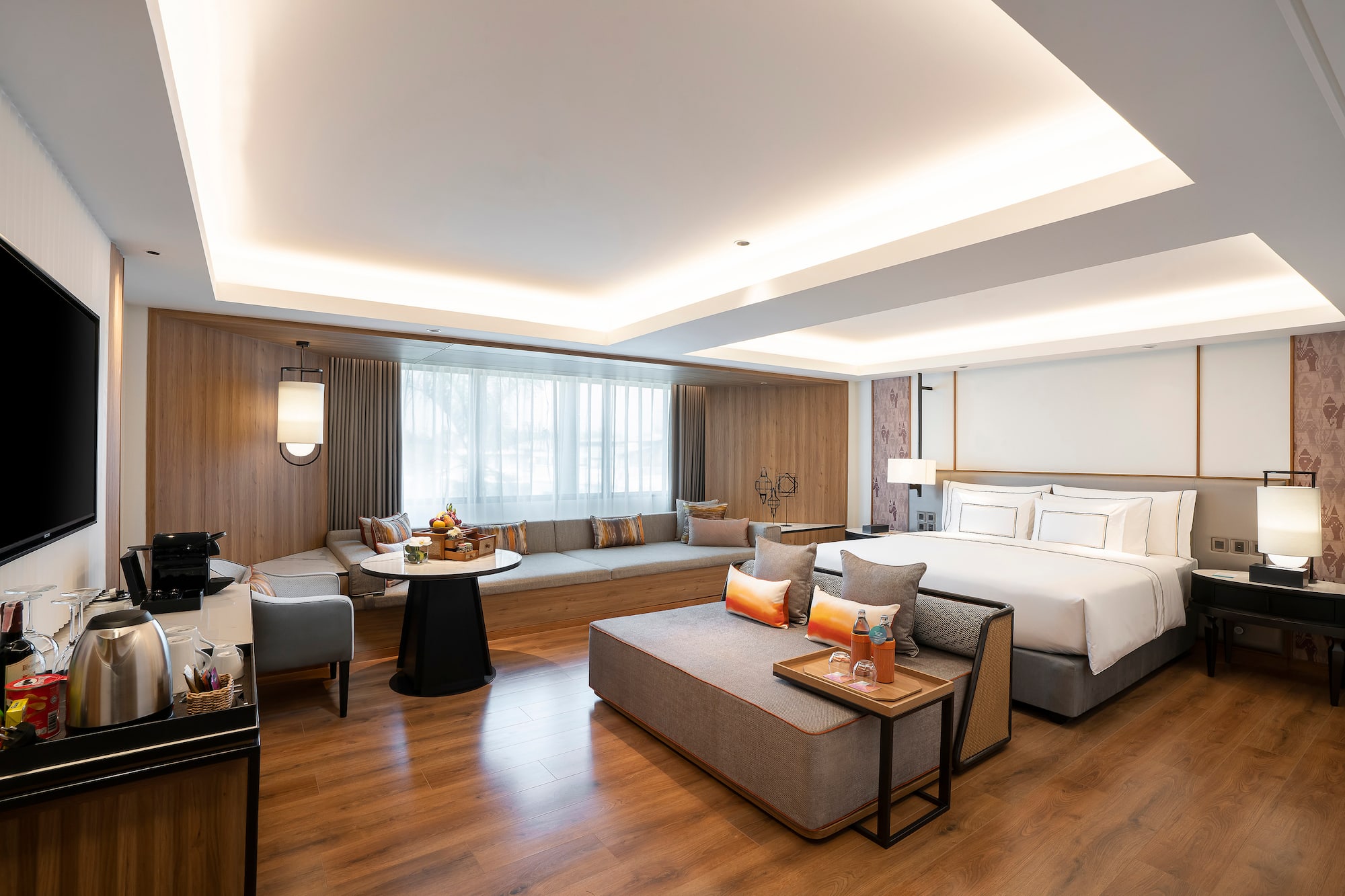Lujosa suite de hotel con cama, sofá, área de estar y ventanal moderno.