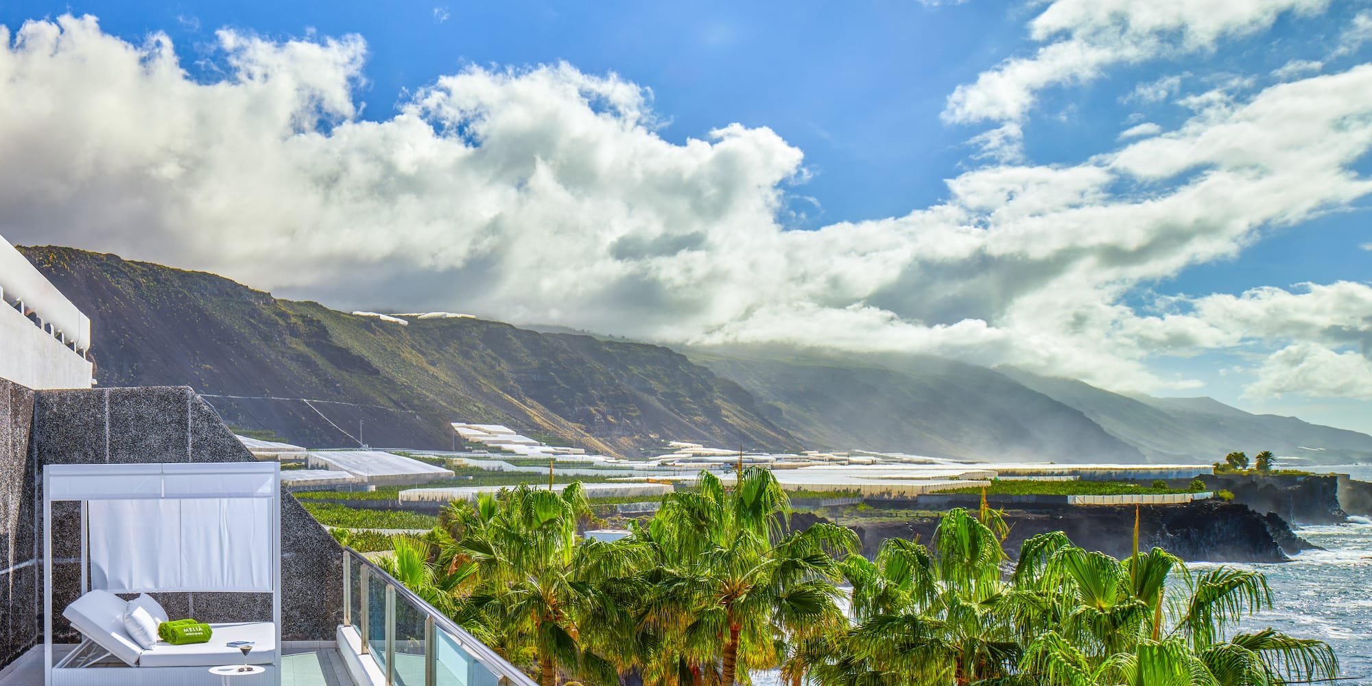 a balcony with palm trees and mountains in the background