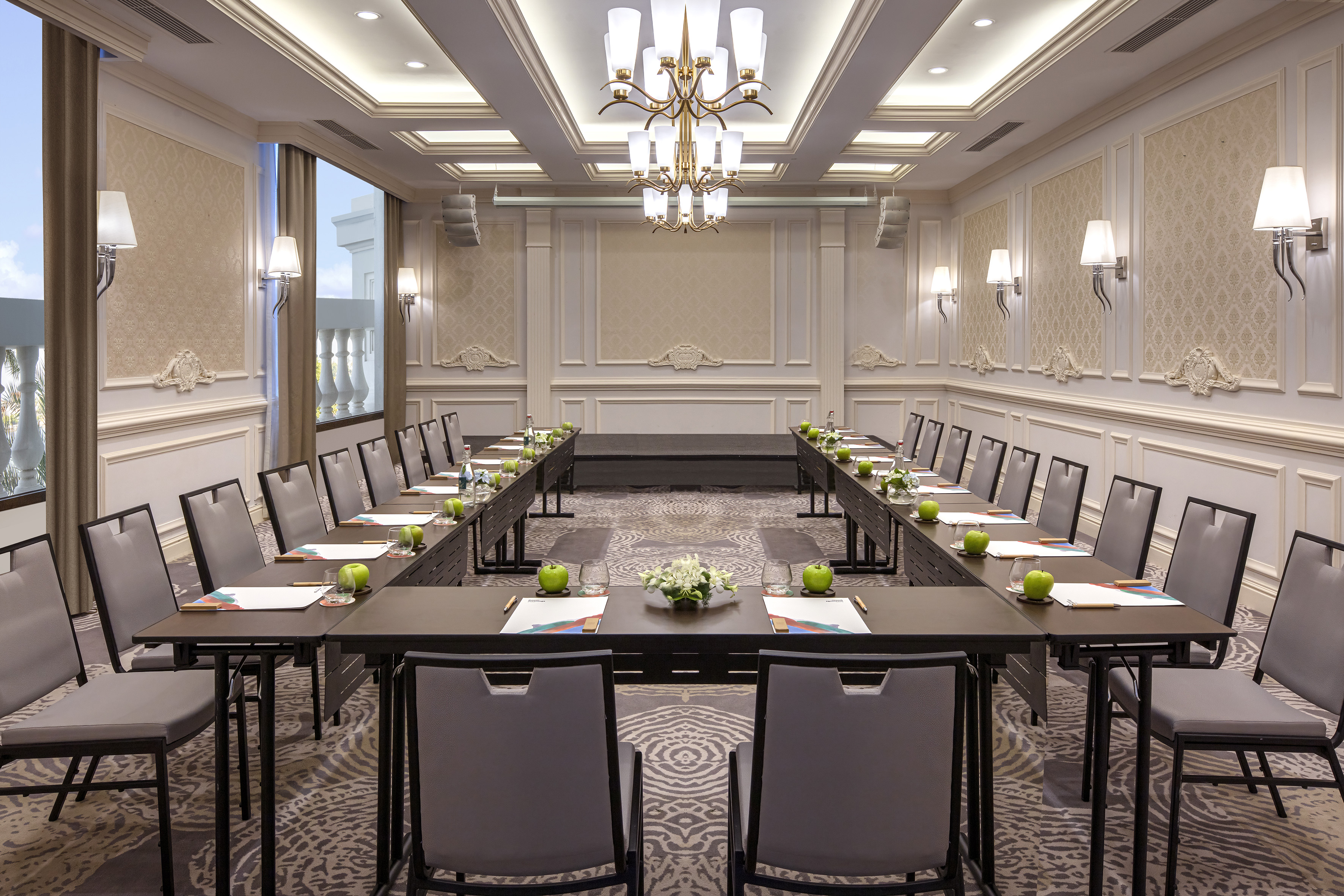 Elegant U-shape conference room with chandelier and stage setup.
