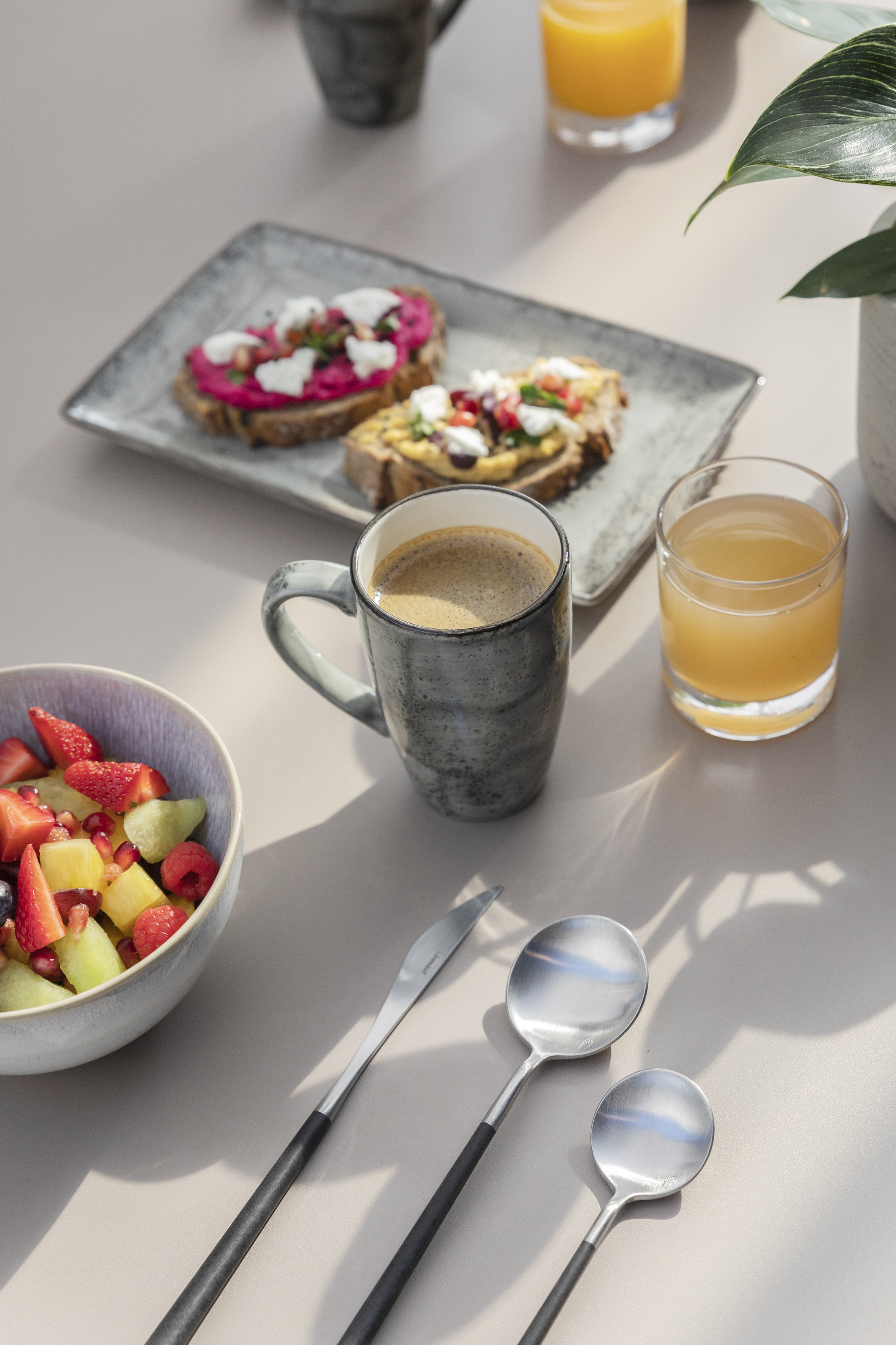 Breakfast with coffee, juice, fruit salad, and colorful open-faced toasts.
