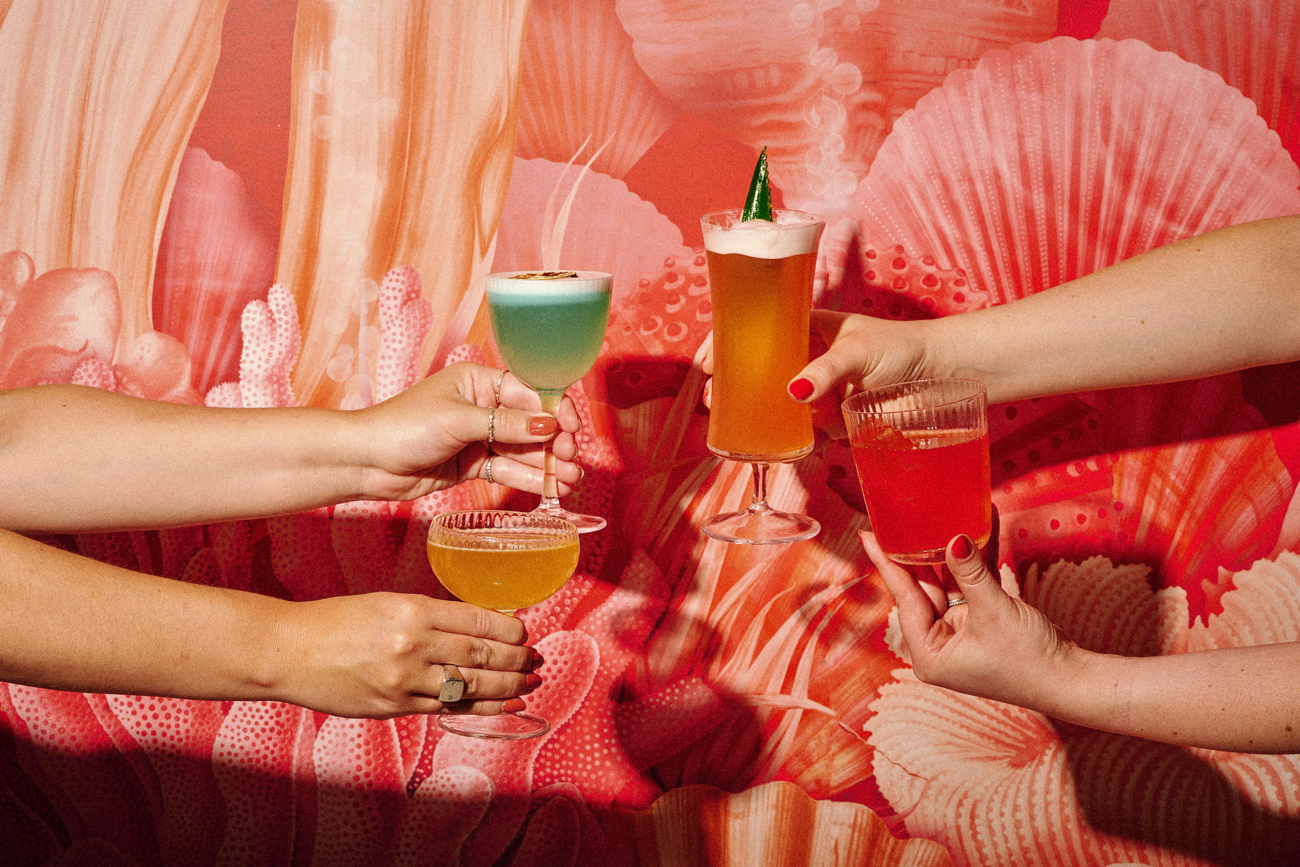 a group of hands holding glasses of drinks
