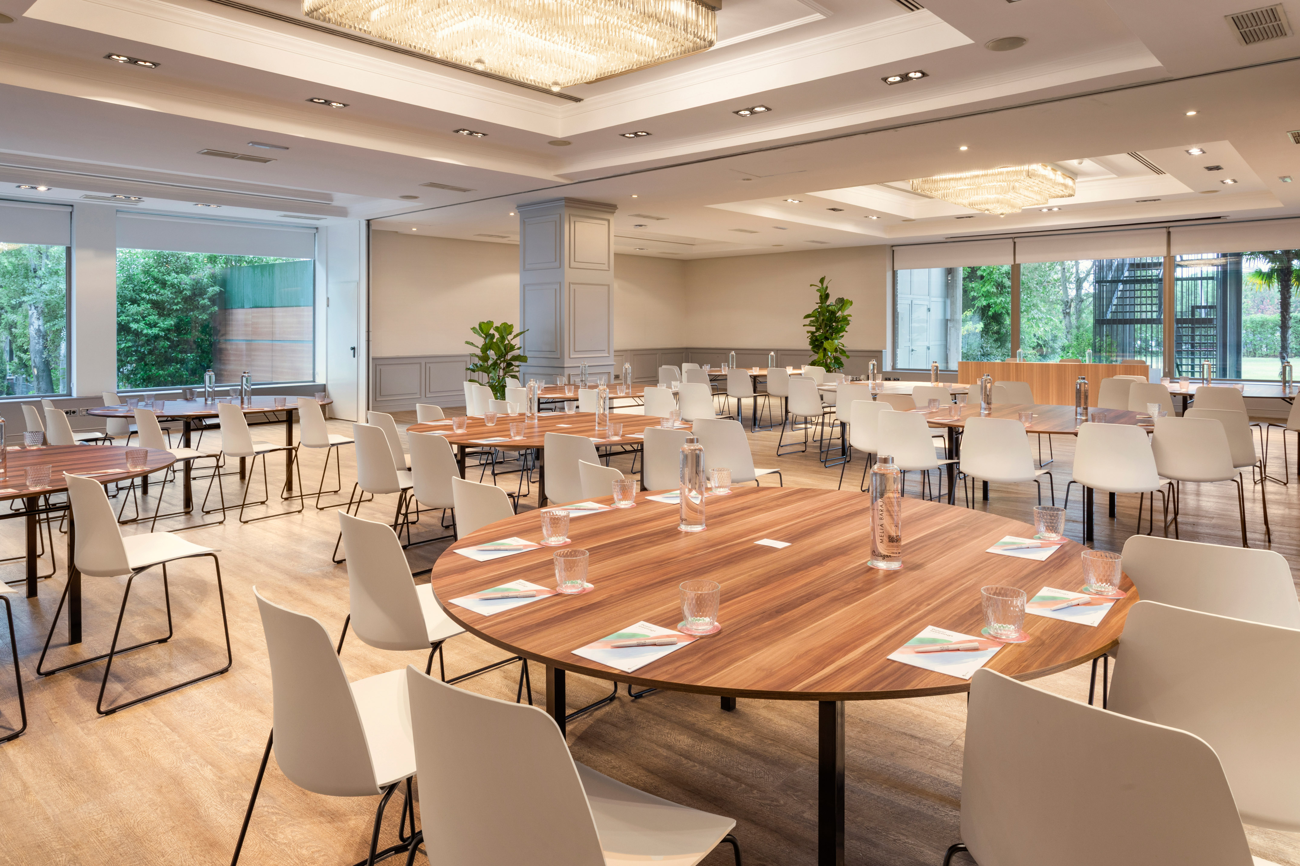Modern meeting room with round tables, white chairs, and large windows.