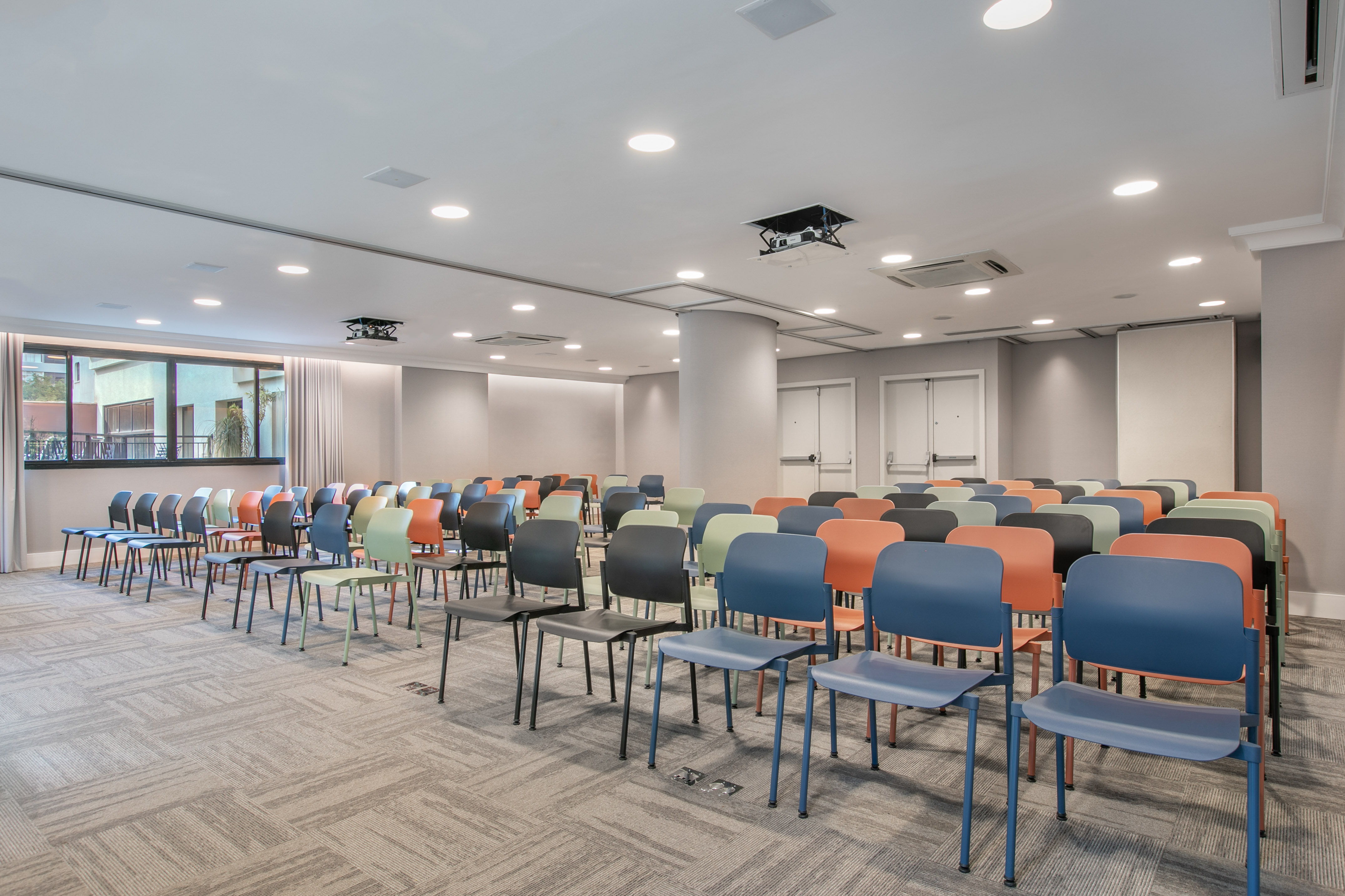 Empty modern meeting room with colorful chairs and ceiling projector.