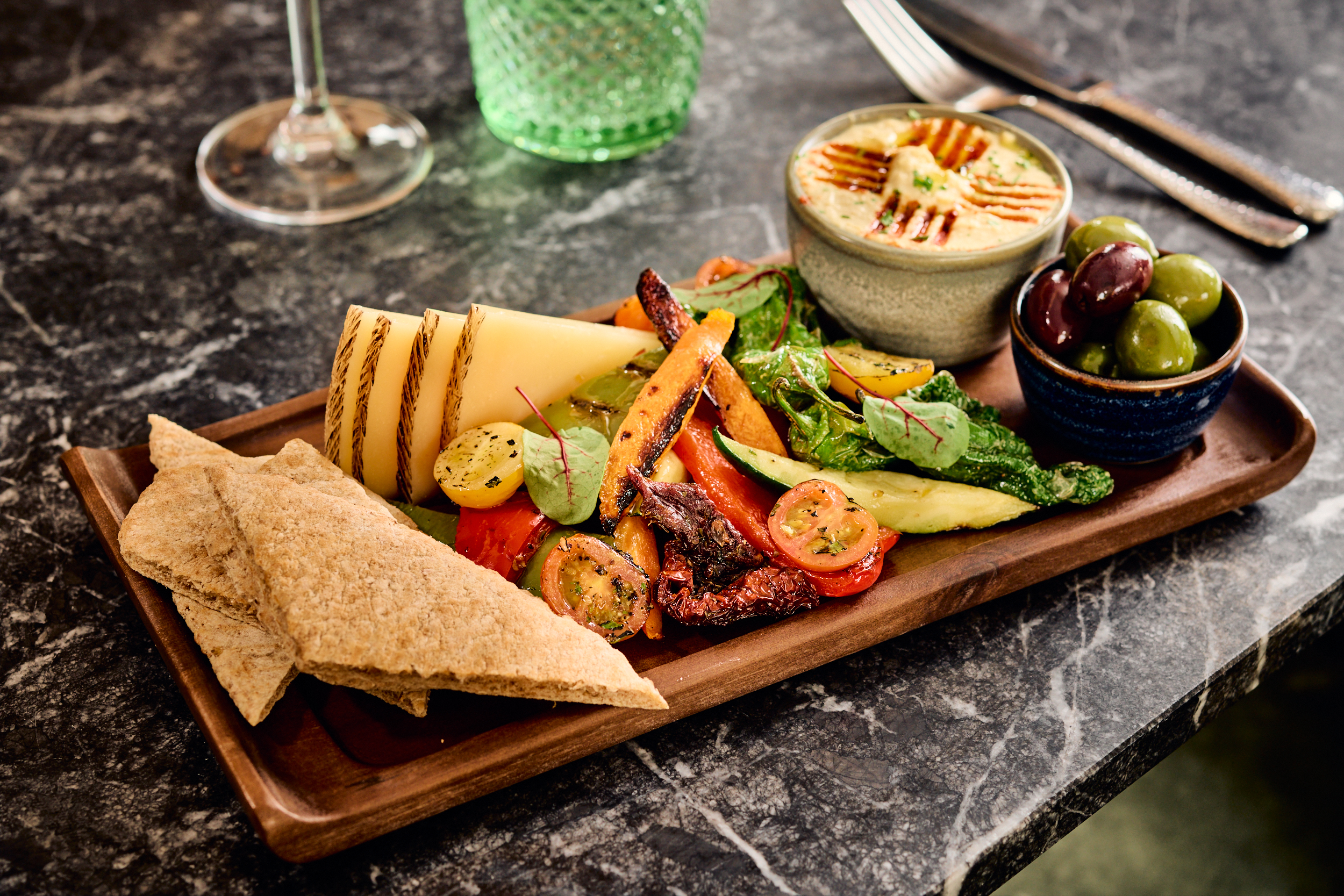 Mediterranean mezze platter with cheese, hummus, roasted vegetables, olives, flatbread.