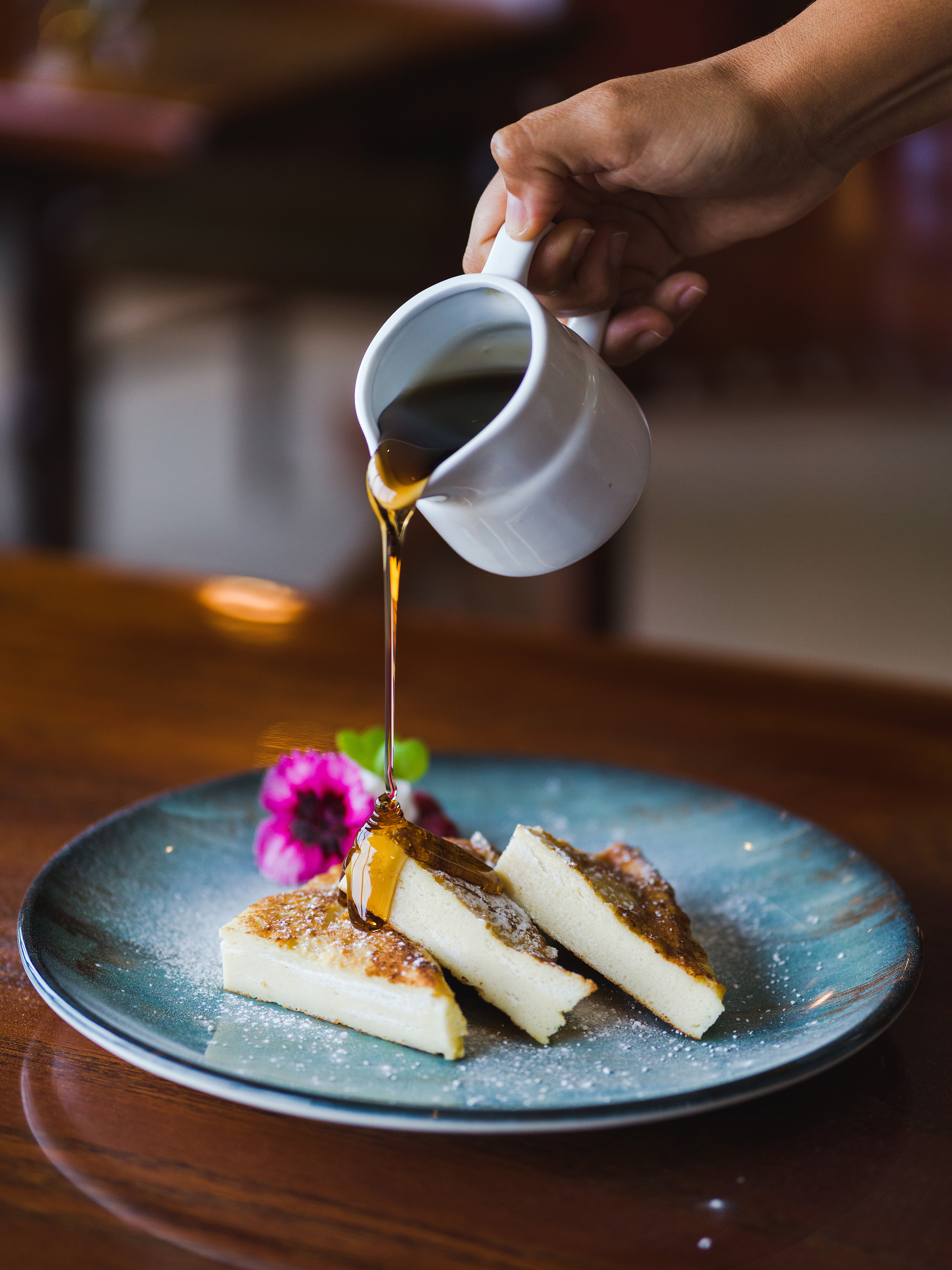 a person pouring syrup on a plate of food
