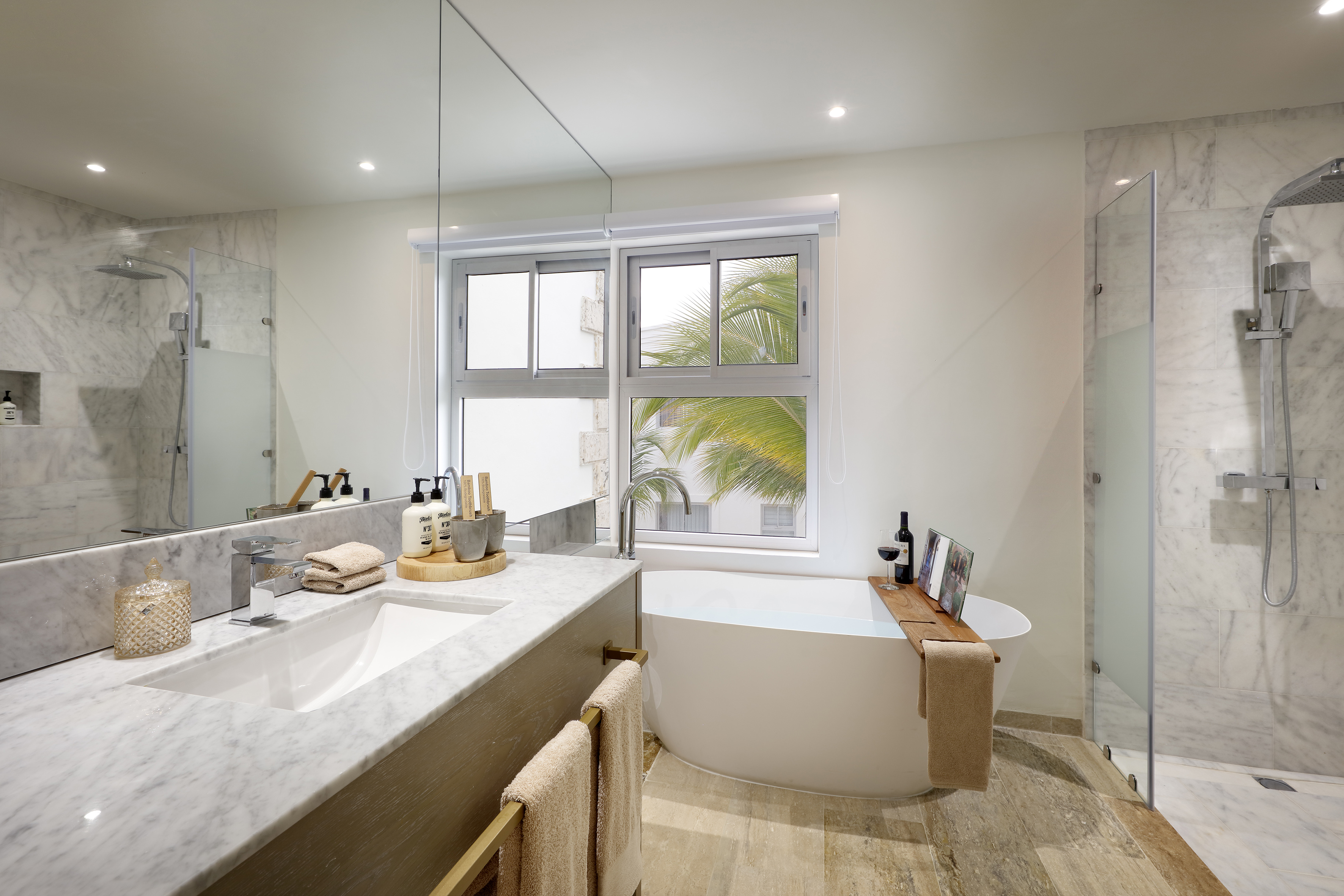Contemporary spa bathroom with freestanding tub, marble shower, and tropical window.
