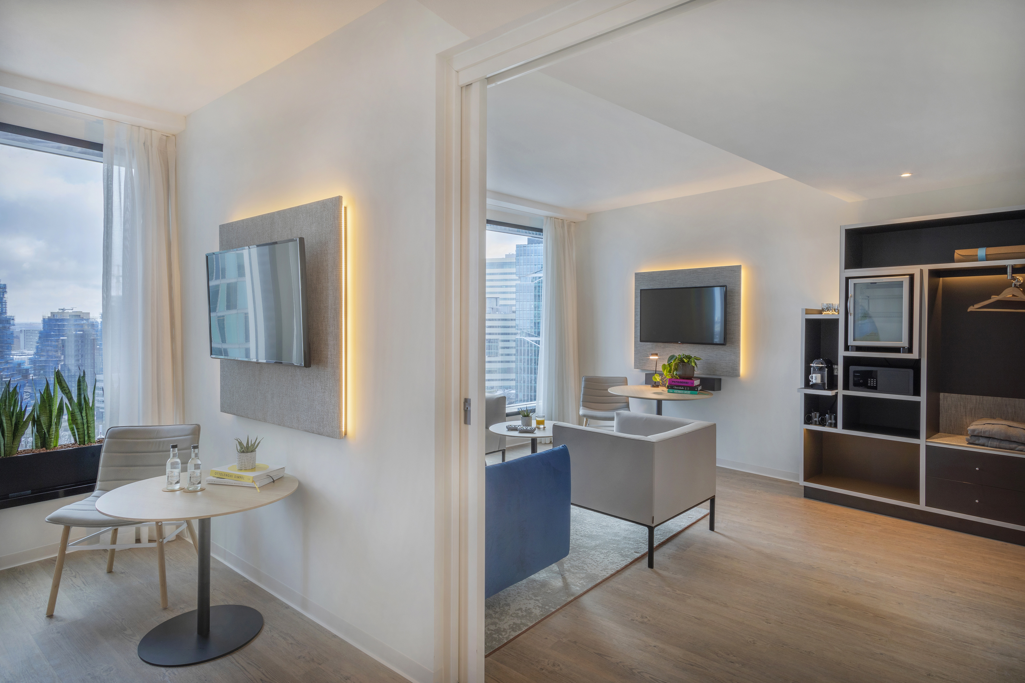 Modern hotel suite with living area, dining space, and city view.