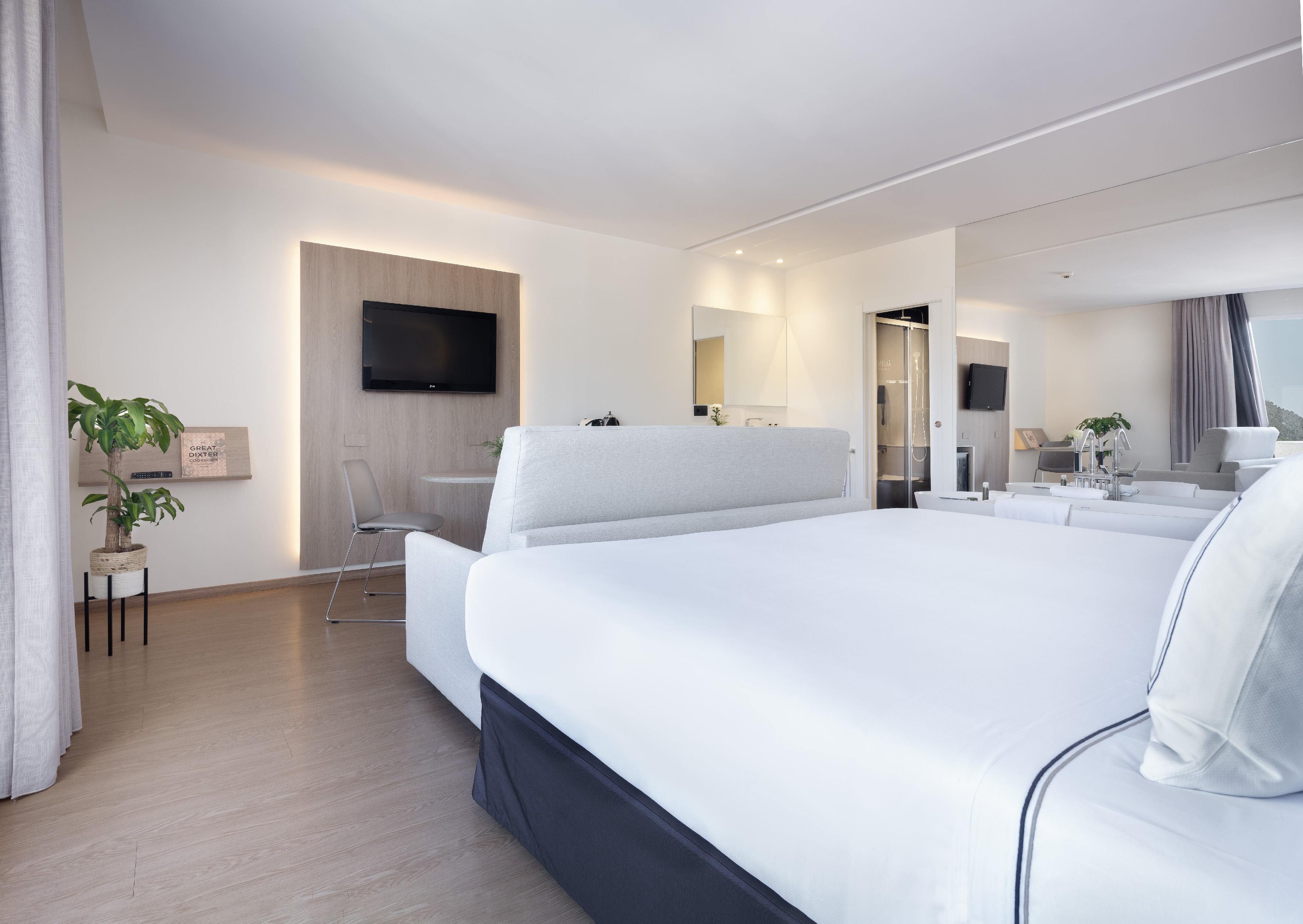 Luxury hotel room with large bed, modern decor, and integrated living space.
