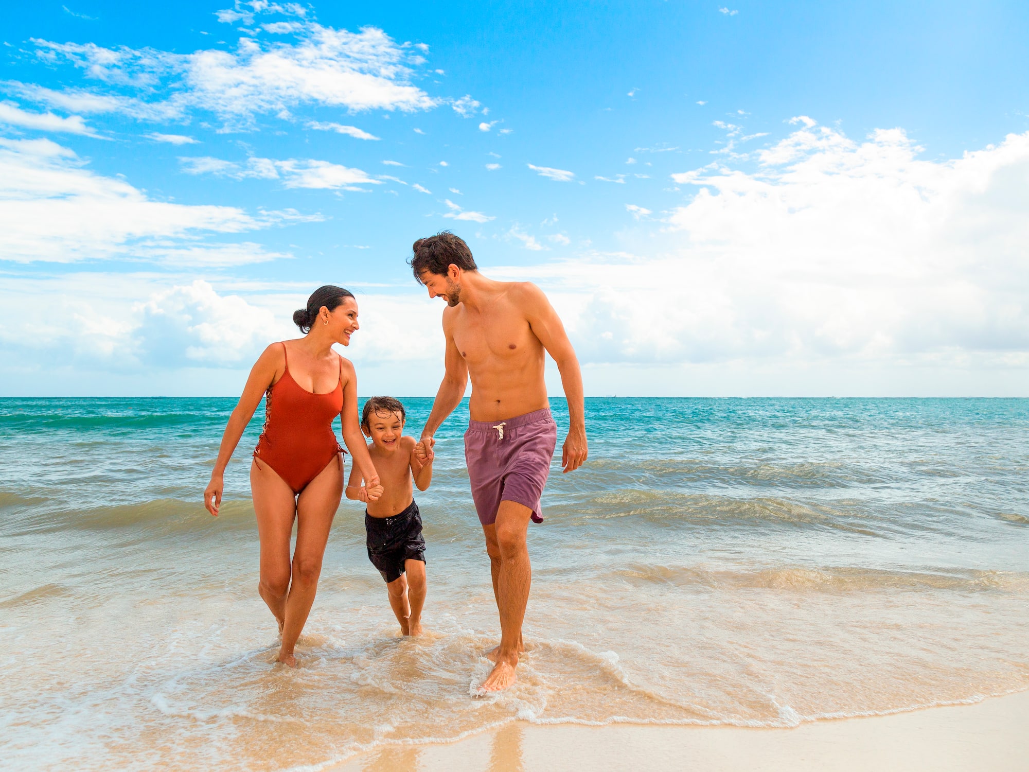 a man and woman holding hands and a child walking on a beach