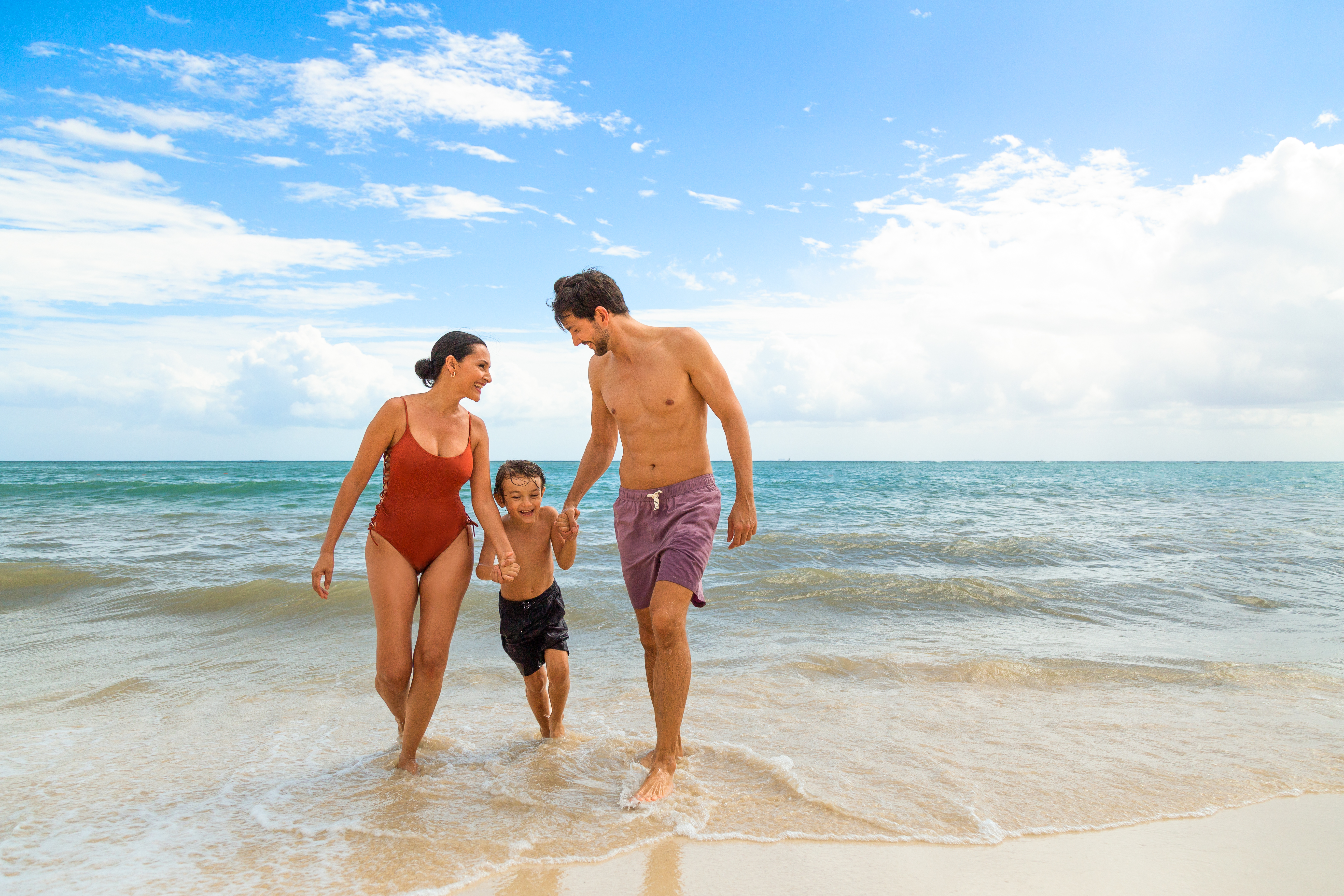 a man and woman holding hands and a child walking on a beach