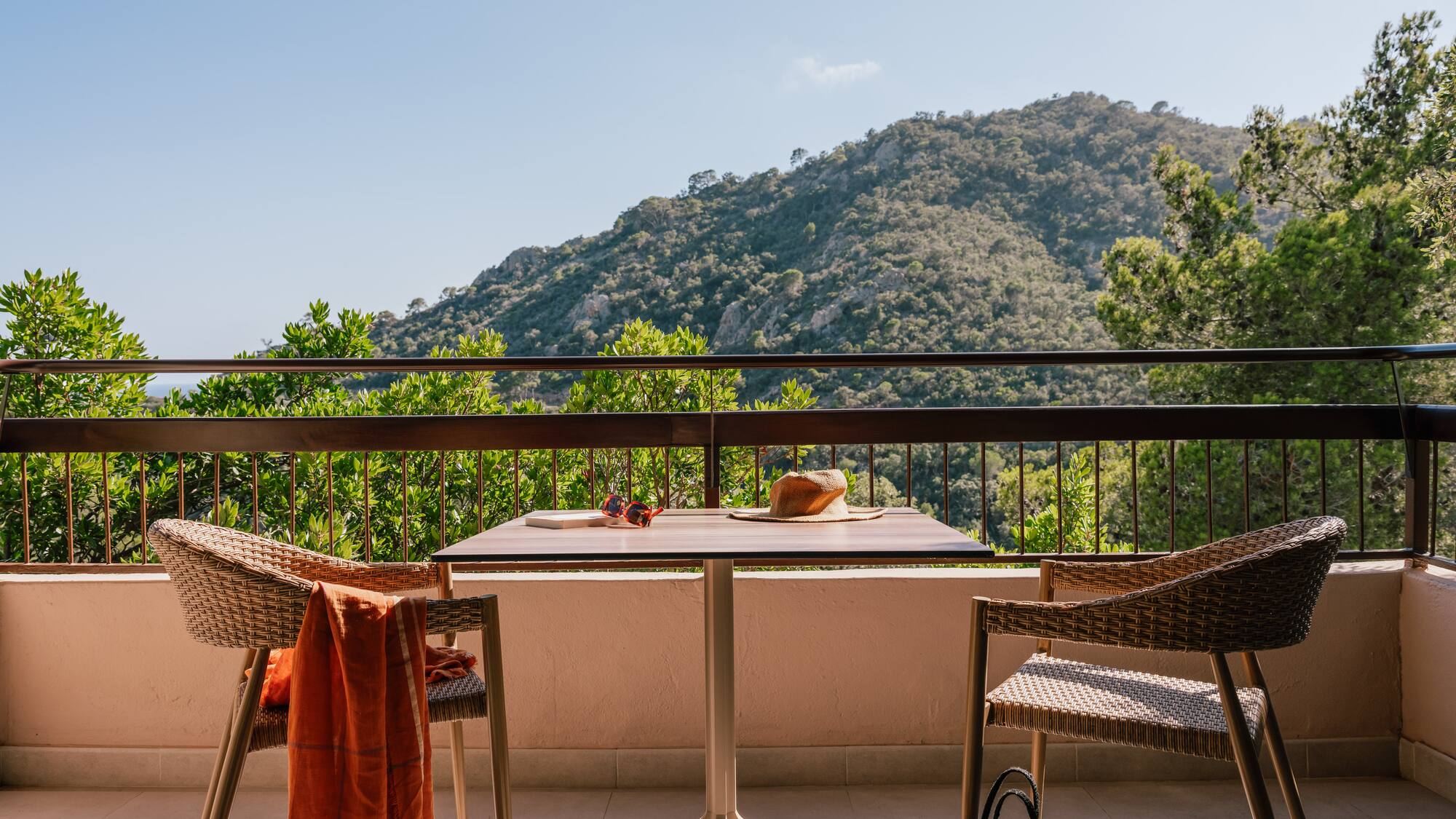 a table and chairs on a balcony overlooking a mountain