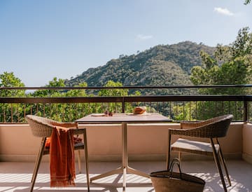 a table and chairs on a balcony overlooking a mountain