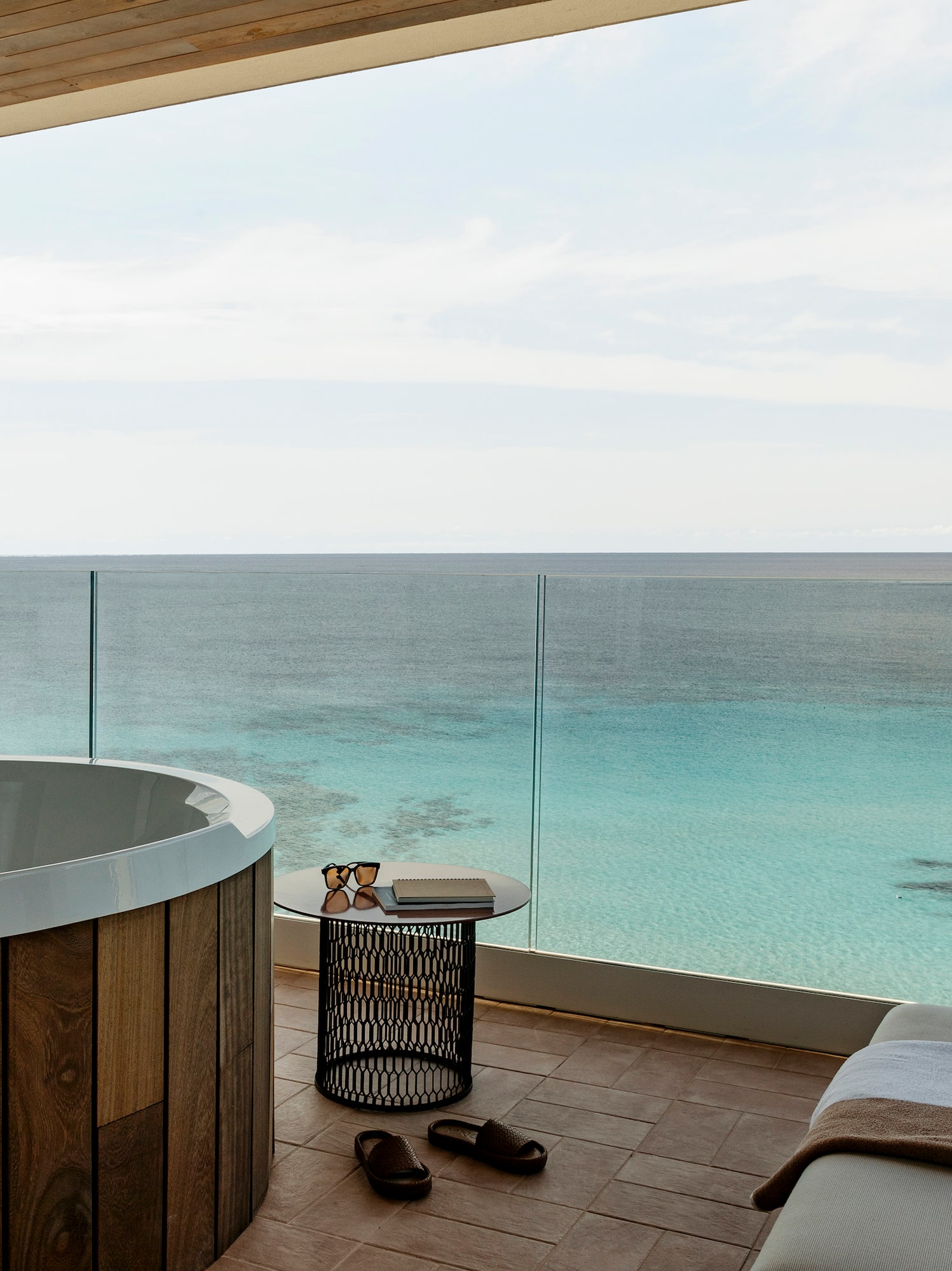Luxury ocean view balcony with outdoor Jacuzzi and turquoise sea.