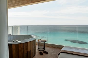 a room with a jacuzzi overlooking the ocean