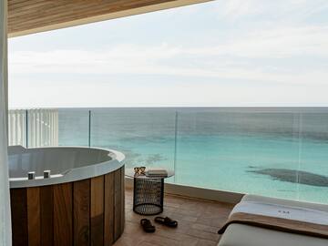 a room with a jacuzzi overlooking the ocean