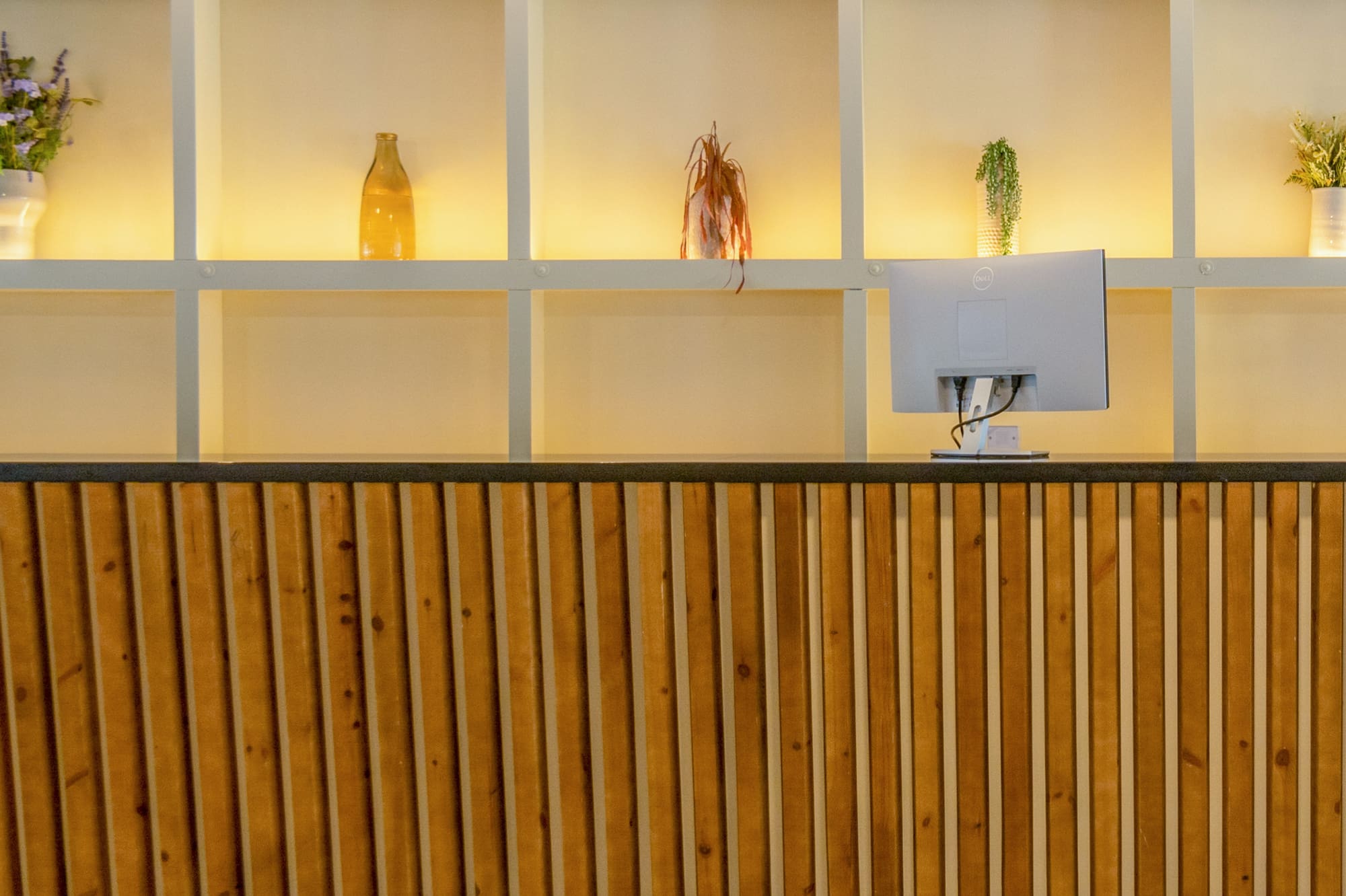 a desk with a computer and shelves in the background