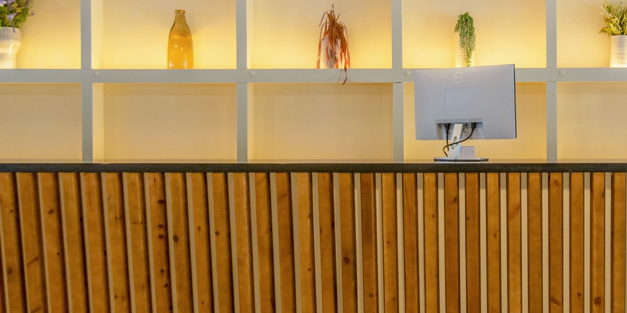 a desk with a computer and shelves in the background