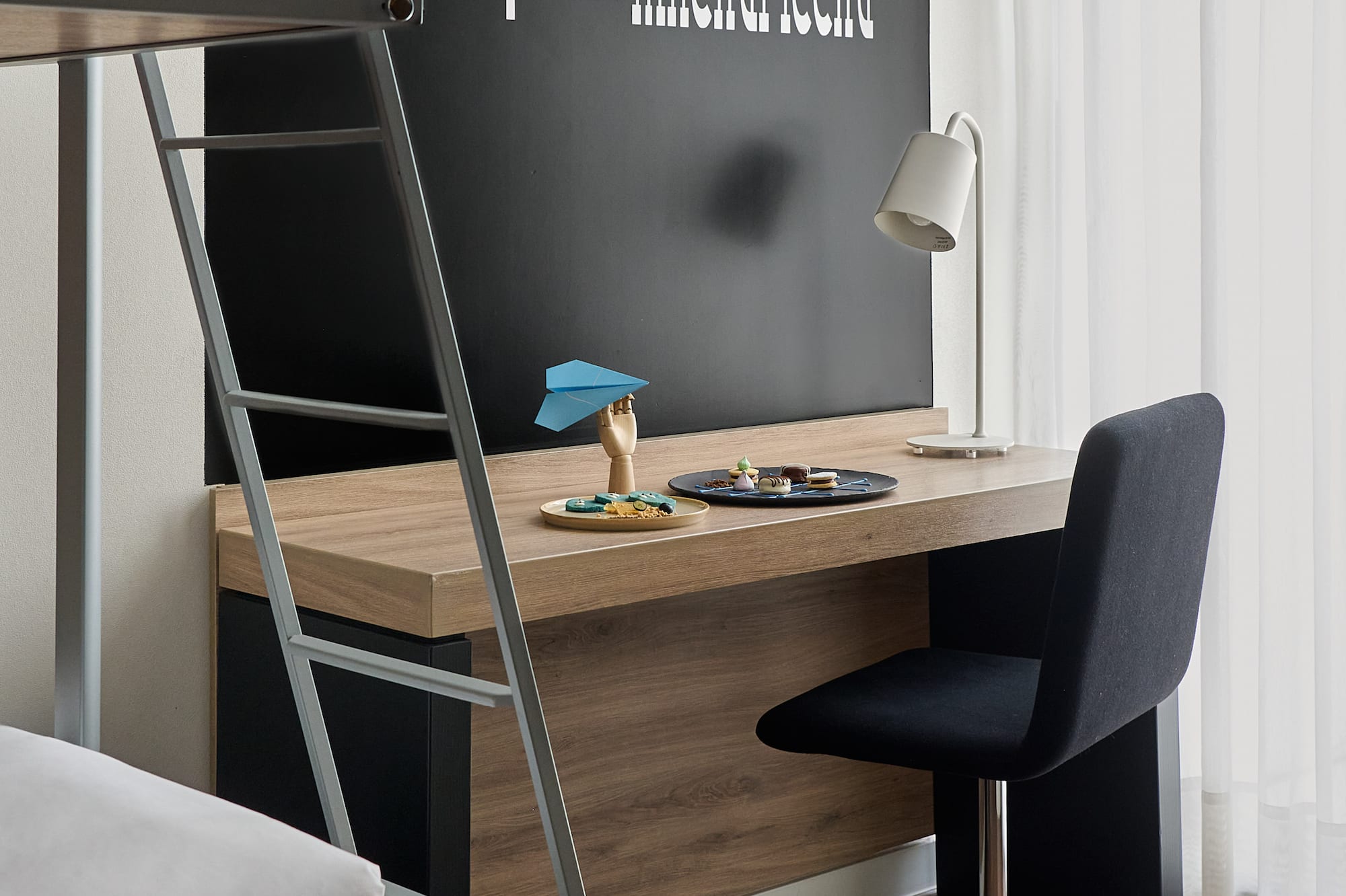 a desk with a ladder and a bed