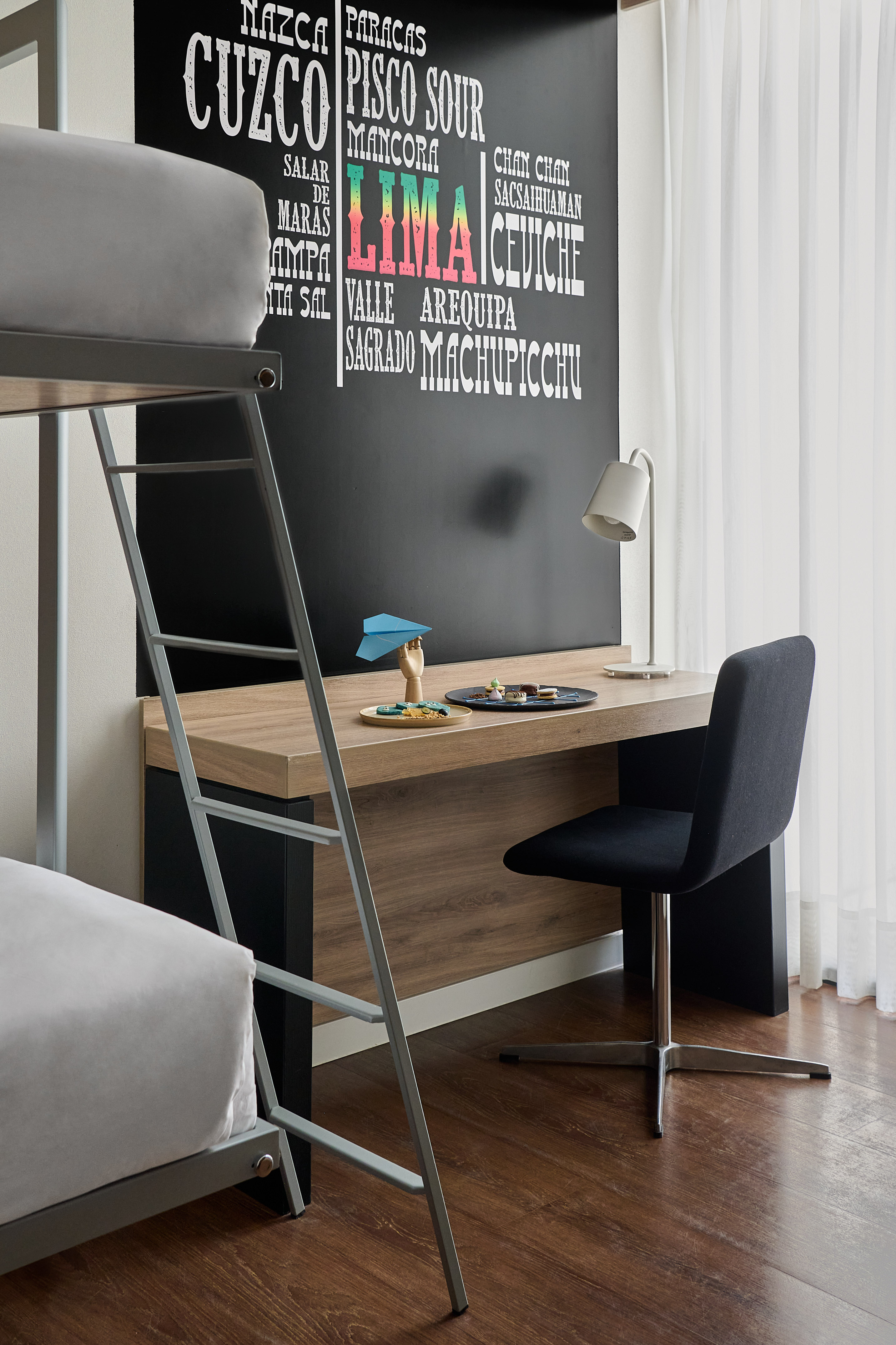 Bunk bed and desk in a room with a chalkboard listing Peruvian places.