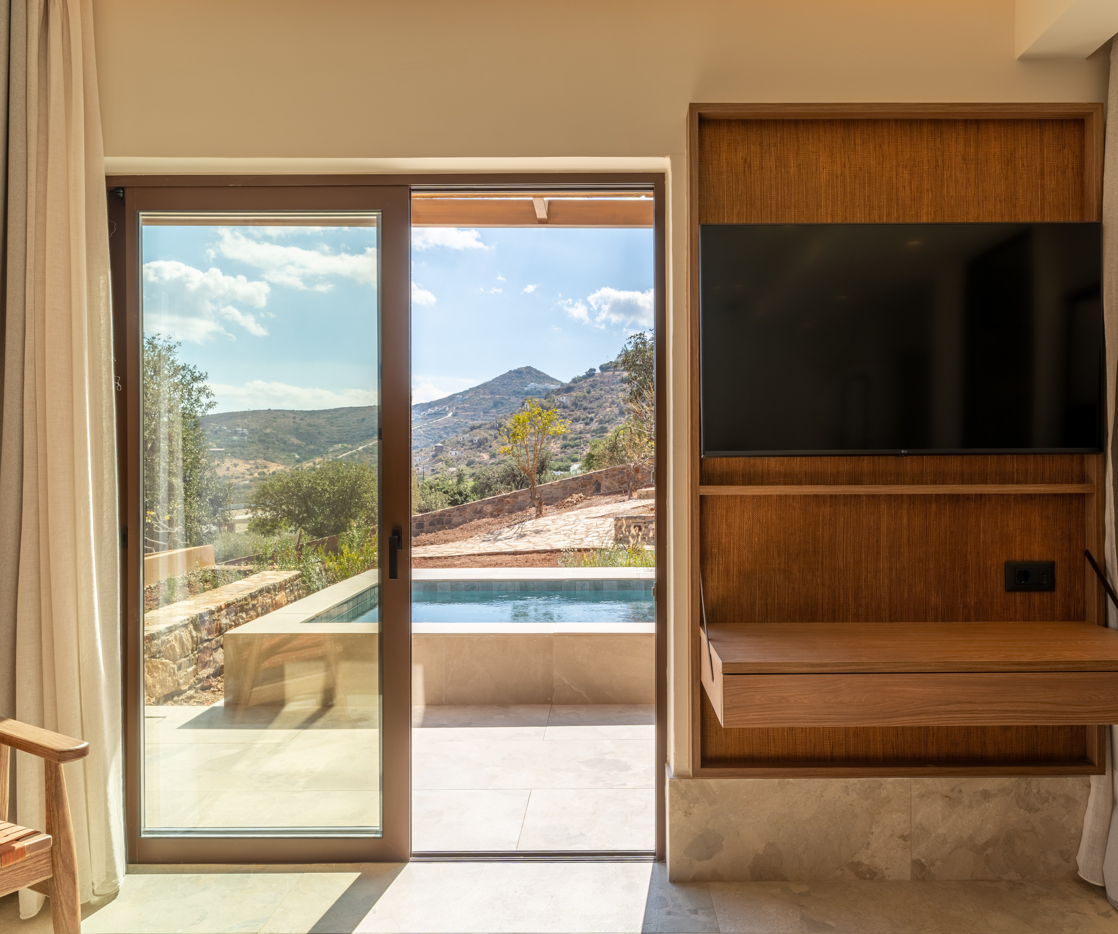 Hotel room with private pool, patio, and scenic mountain view through sliding glass doors.